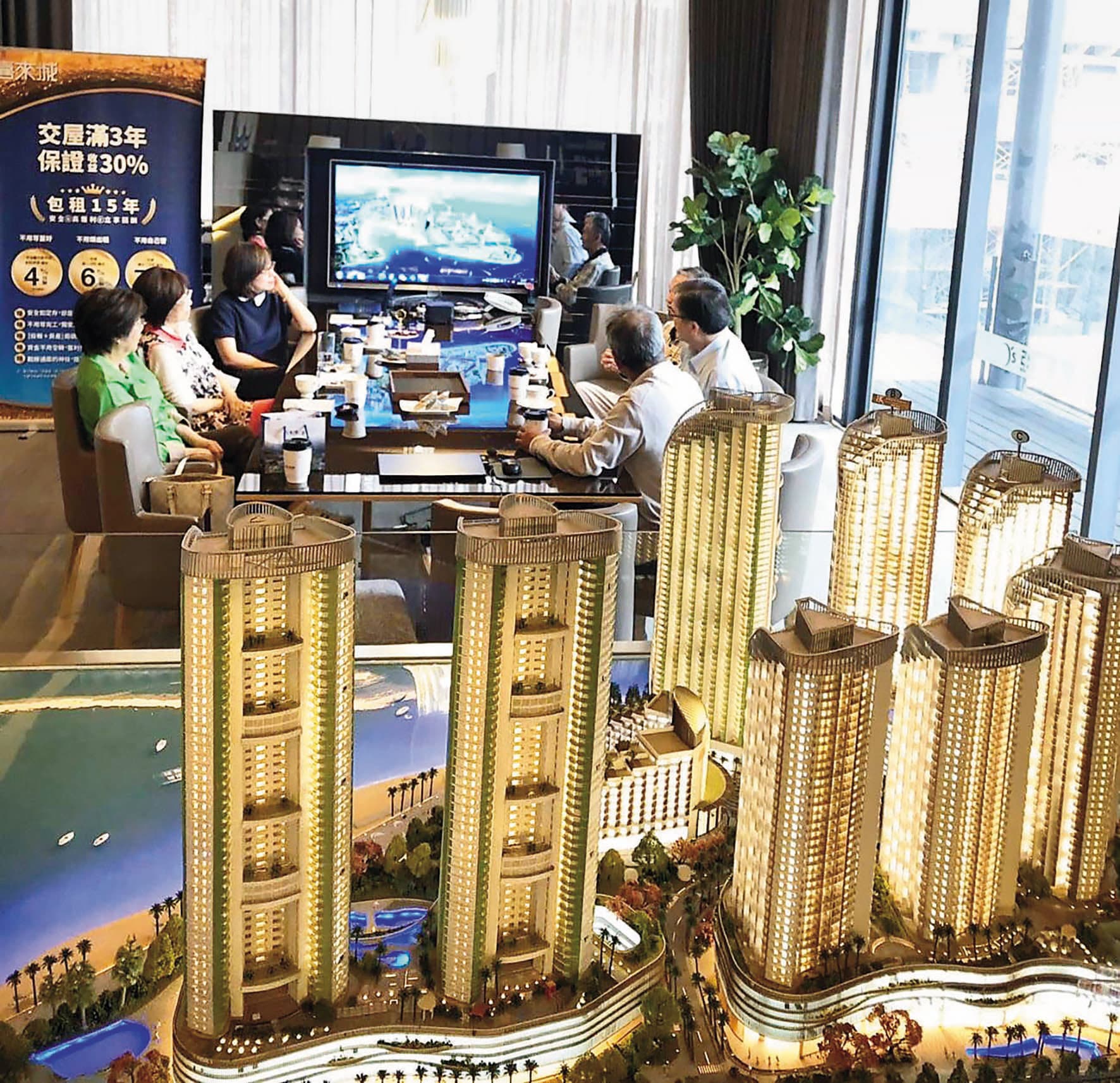 圖為亞昕The Rise銷售中心展示模型,現場接待人員向客戶介紹建案。(翻攝亞昕喜來城臉書粉專)