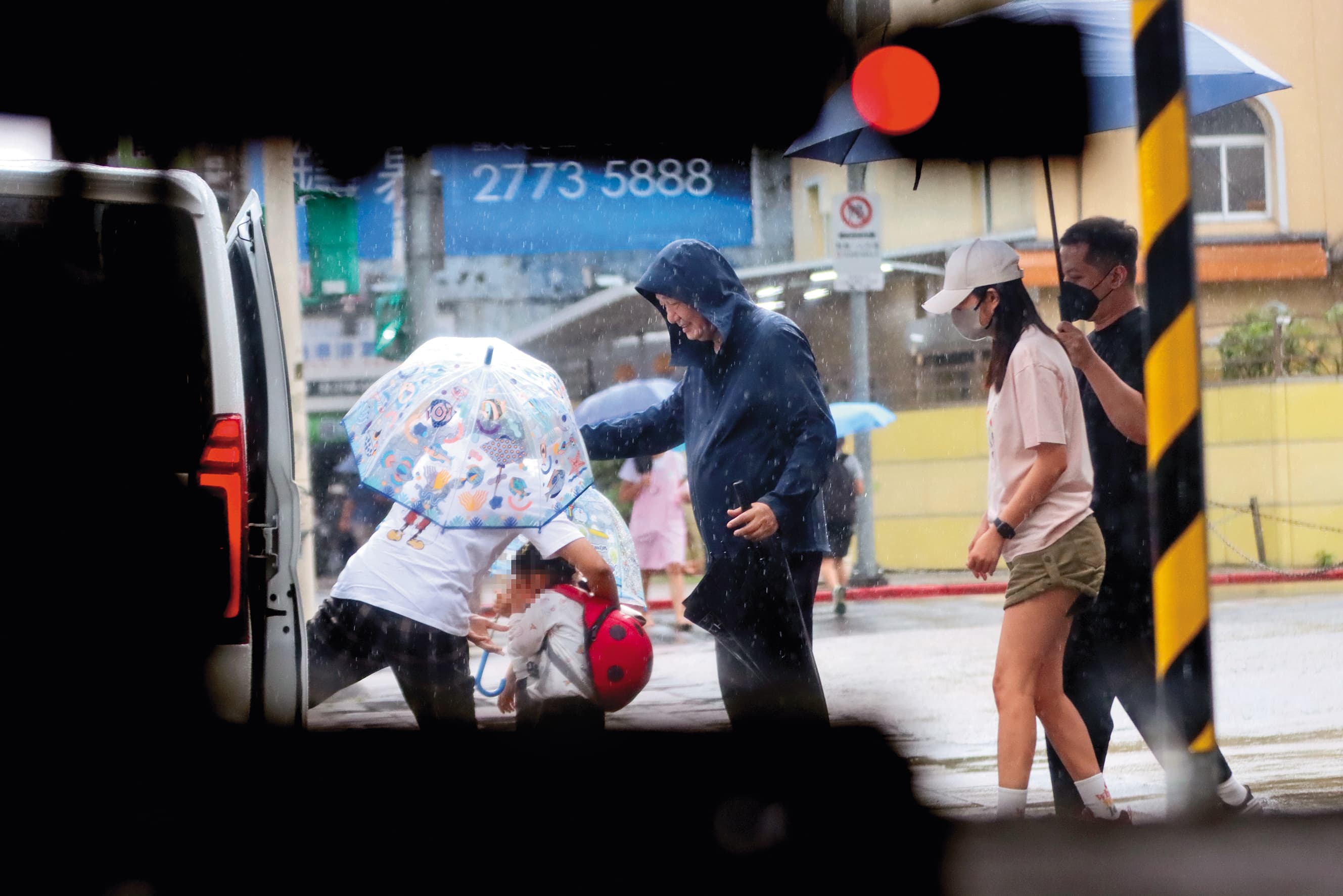8/15 16:21 移工(左一)先把未滿4歲的妹妹抱上車,幼兒園師長(中)也來照應。