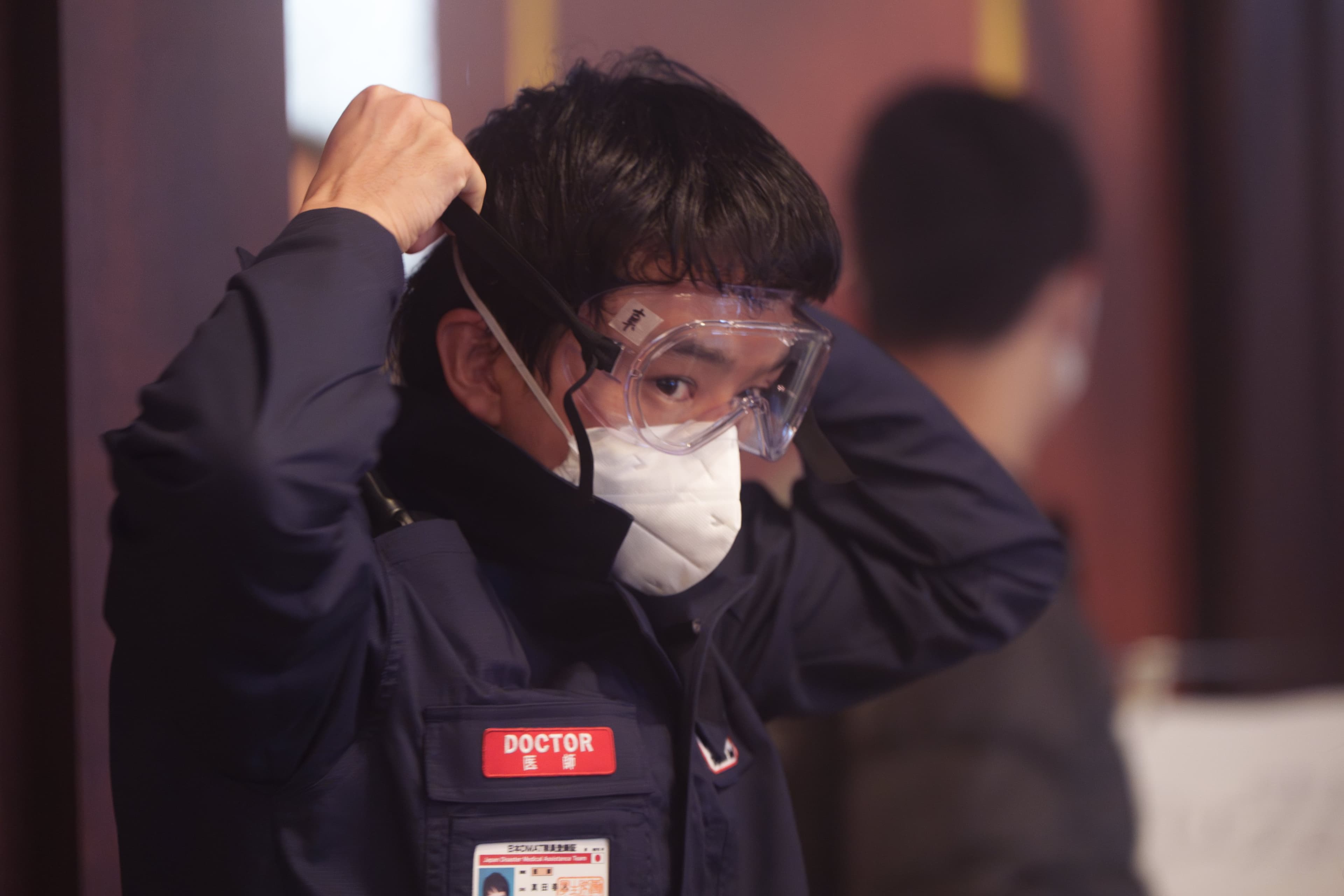 日星池松壯亮在片場堅持長時間佩戴N95口罩，休息時間也不取下。（翻攝《戰疫前線》官方X）