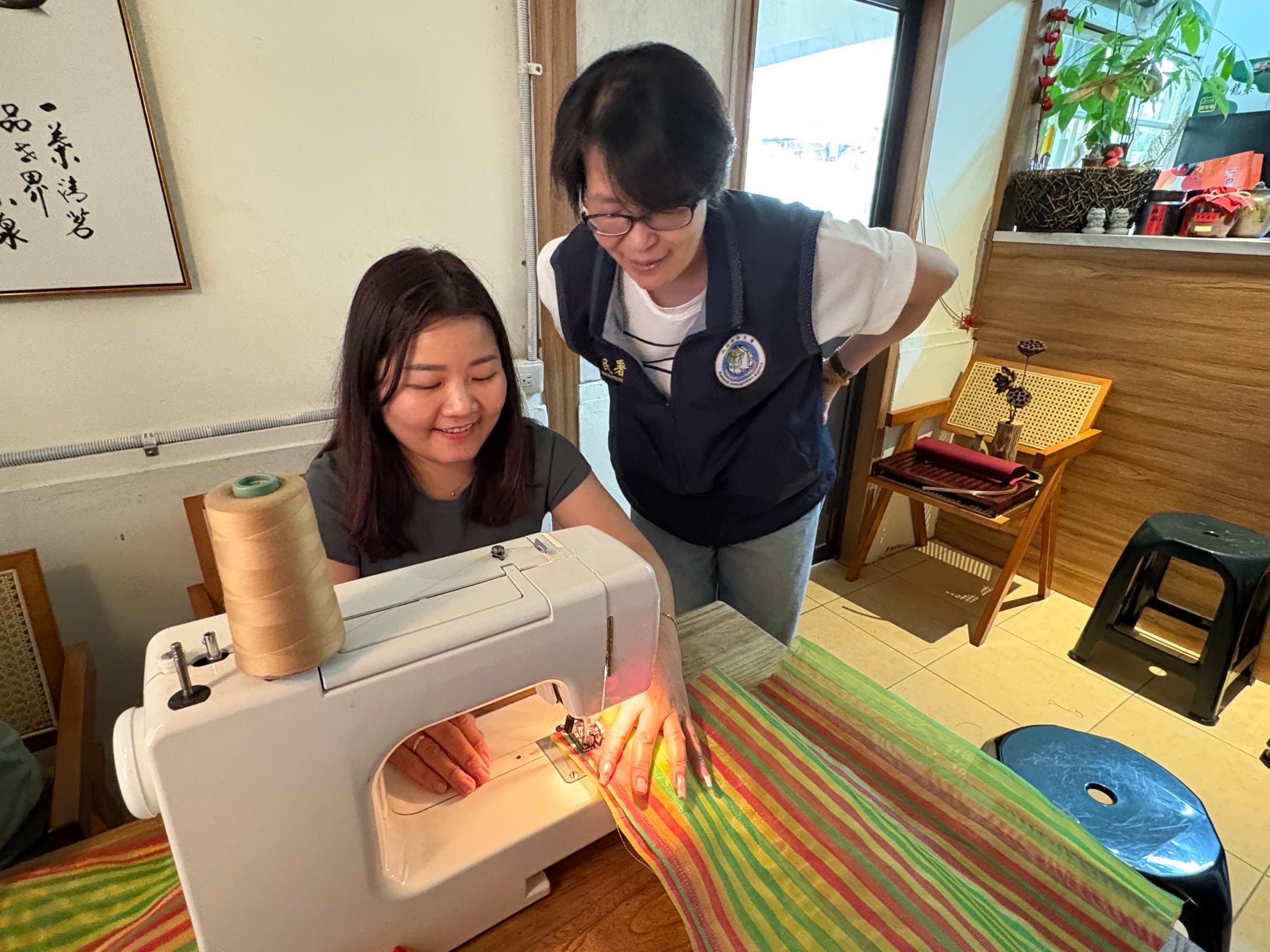 新住民紅青(左)開心地製作屬於自己的茄芷袋,嘉義市服務站主任黃艷薰(右)在旁觀看。(移民署提供)