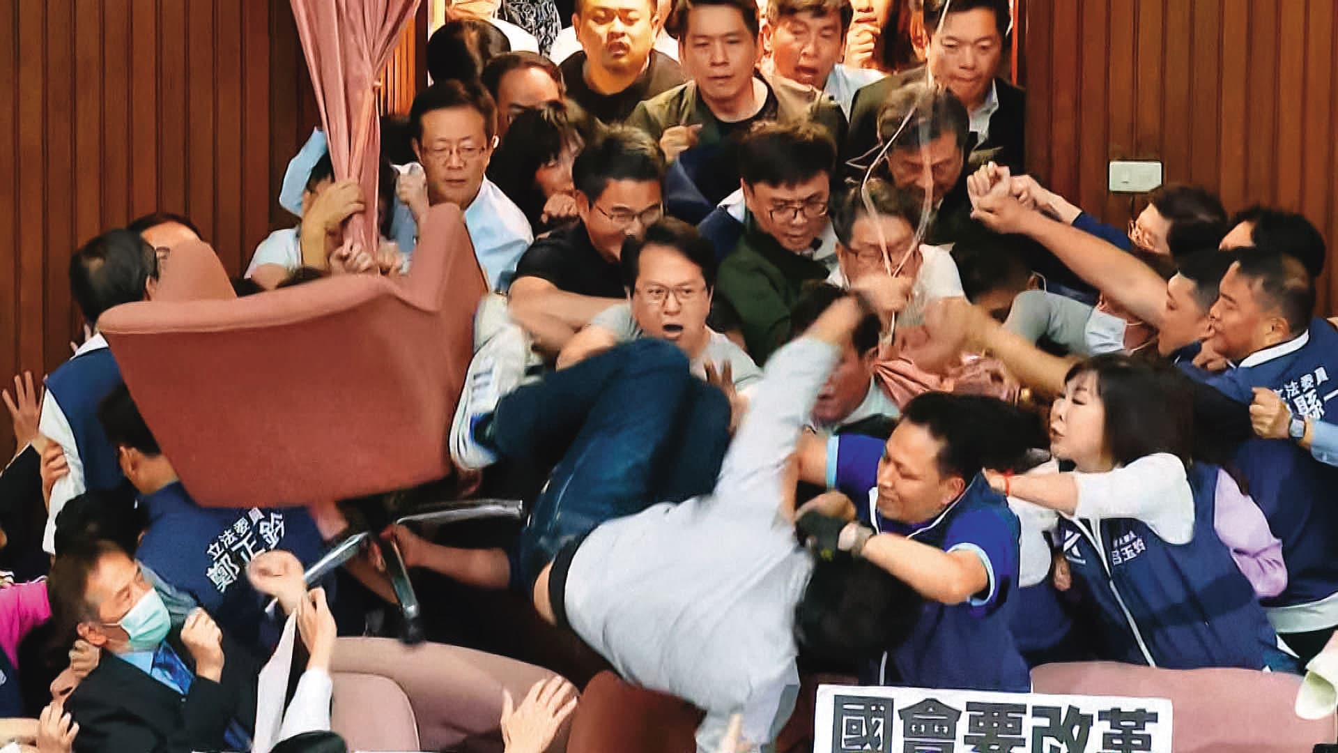 民進黨從正面進攻主席台,多人因此摔傷。圖為沈伯洋從主席台摔落。(翻攝鏡新聞)