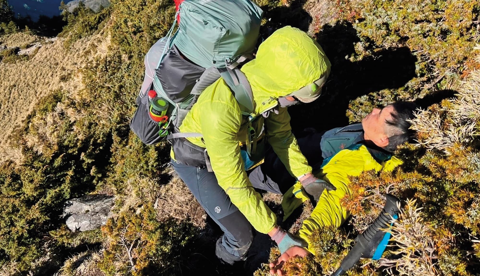 楊守義(右)於南橫公路以南至卑南主山間訓練途中不慎摔落山坡,現場夥伴緊急協助下山。(活水文化提供)