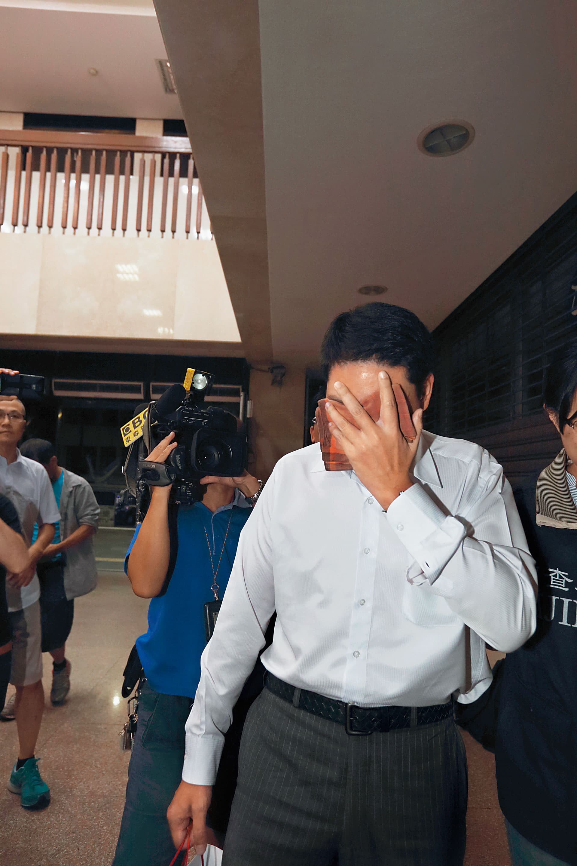 樂陞董事許金龍的哥哥許世龍被約談時用手遮臉,不敢面對鏡頭。