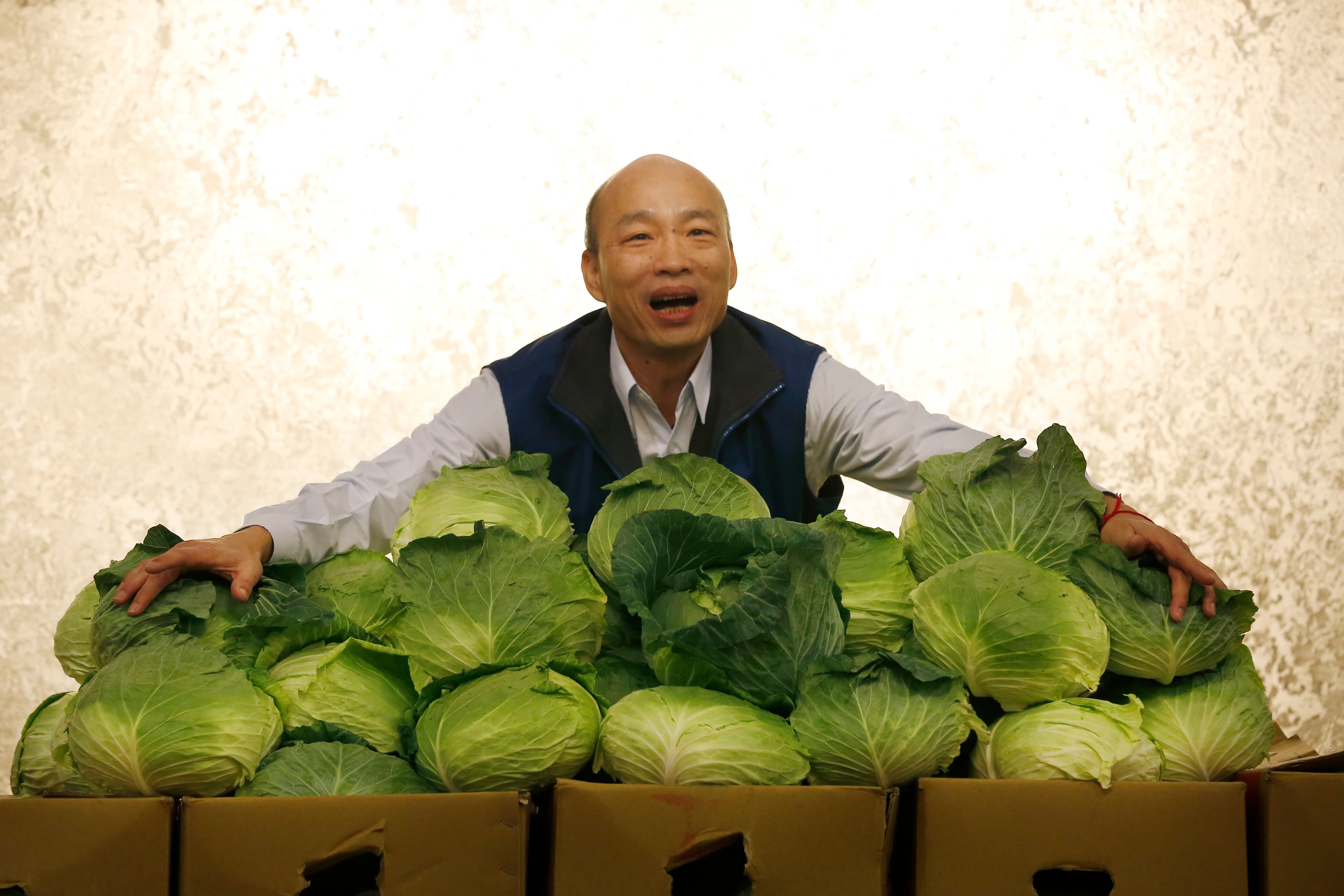 韓國瑜作勢擁抱甘藍菜表示,自己頭型很像甘藍菜,這種菜是台灣最平價的蔬果,代表他擁抱民意,永遠與民意站在一起。