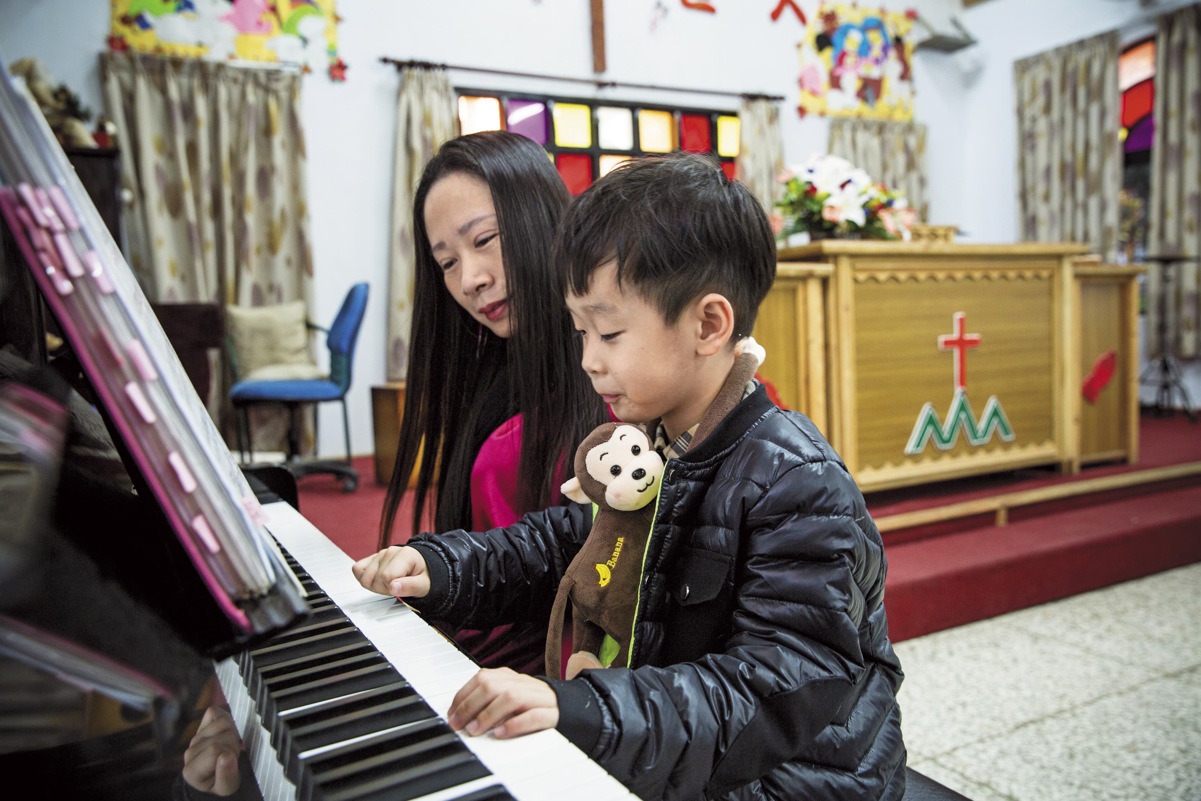 楊恩典一家人幾乎每週都回六龜育幼院教會做禮拜。禮拜後,小兒子練習彈琴,楊恩典在一旁相伴。