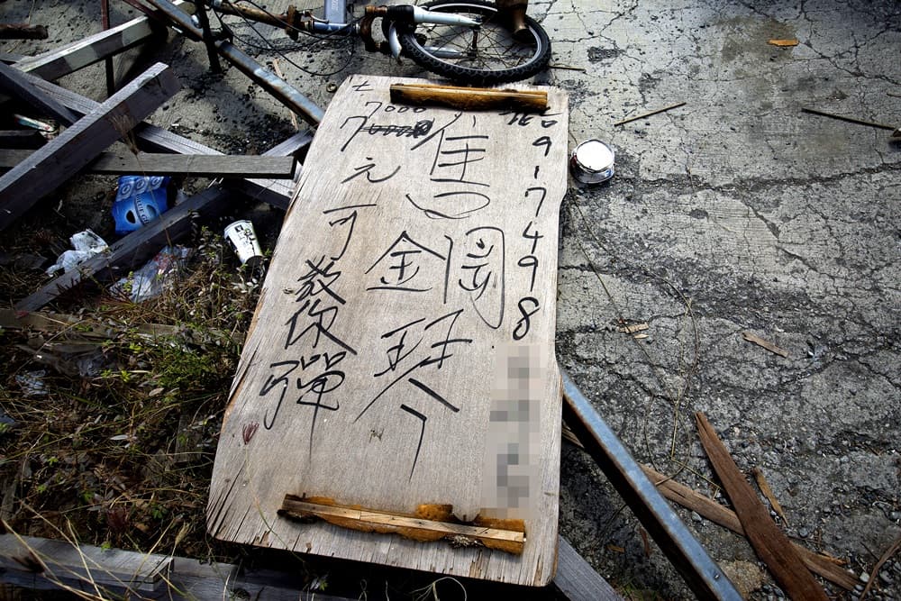 周進田在木板上潦草寫著招生廣告「7000元可教你彈」,可惜至今未有人報名。