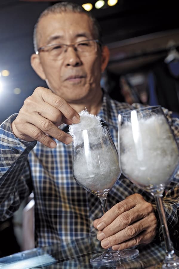 方顯裕是羽毛專家,徒手觸摸就能分辨羽絨比例。左為添加備長炭3D包覆羽絨纖維的蓄熱羽絨。
