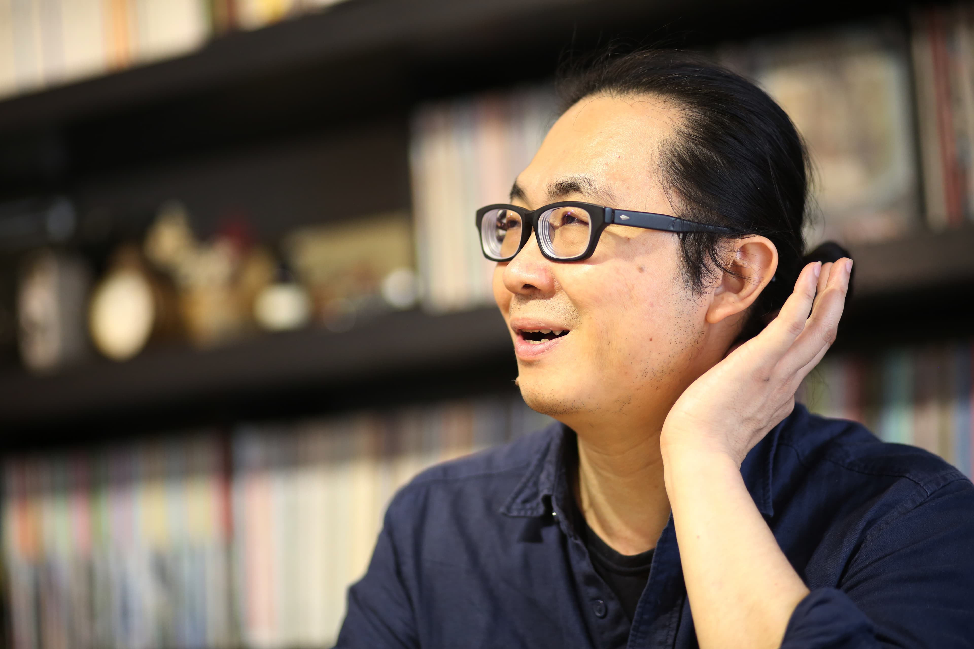 阮光民戴粗框眼鏡、綁馬尾，有藝術家浪漫不羈的氣息。