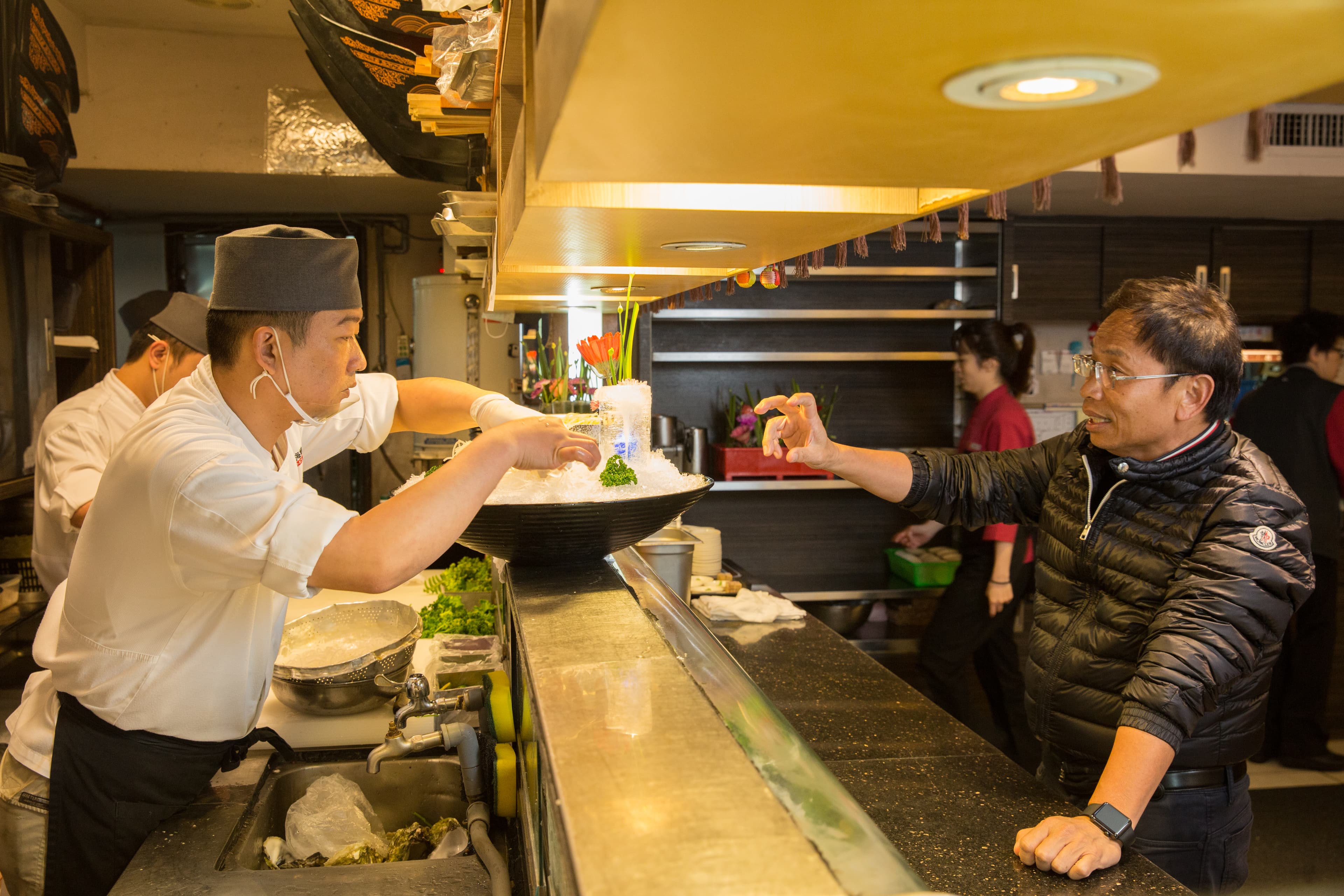 黃文童（右）在餐廳打造專屬的日本料理吧台，對食材、擺盤以及師傅料理手法的要求嚴格，也會親自指導。