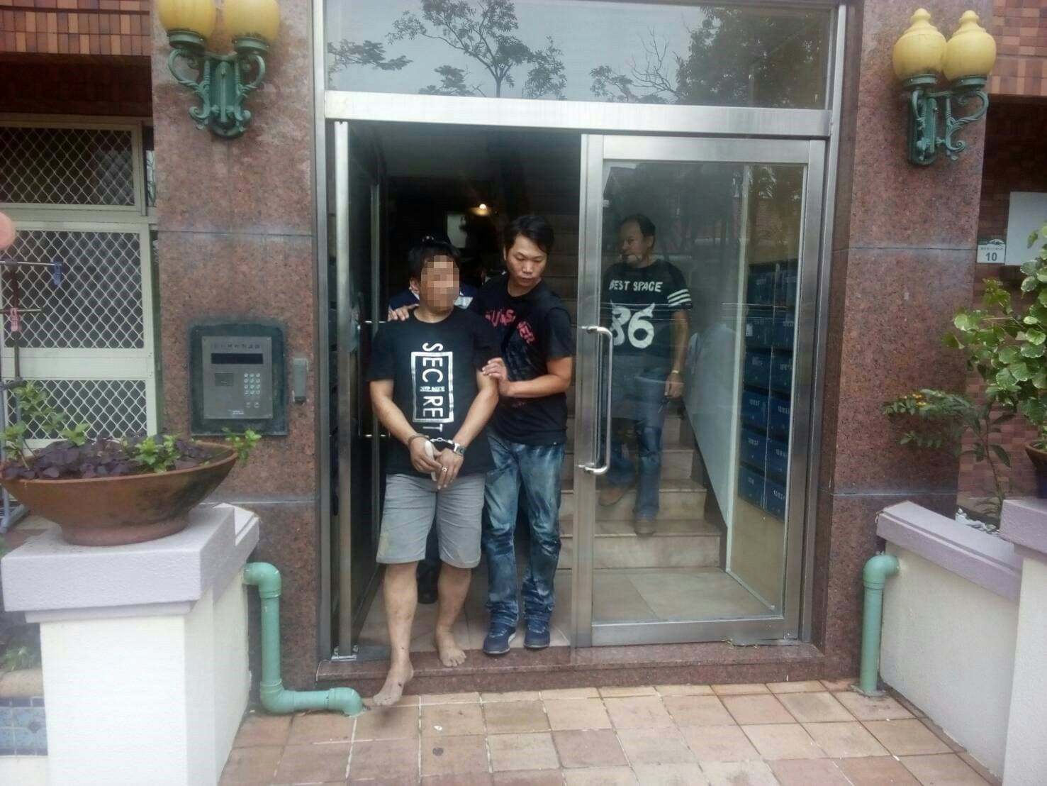 警方逮捕暴力毒品黑吃黑集團,為首的何姓男子因為與警方駁火太緊張,臉色慘白的走出大樓。