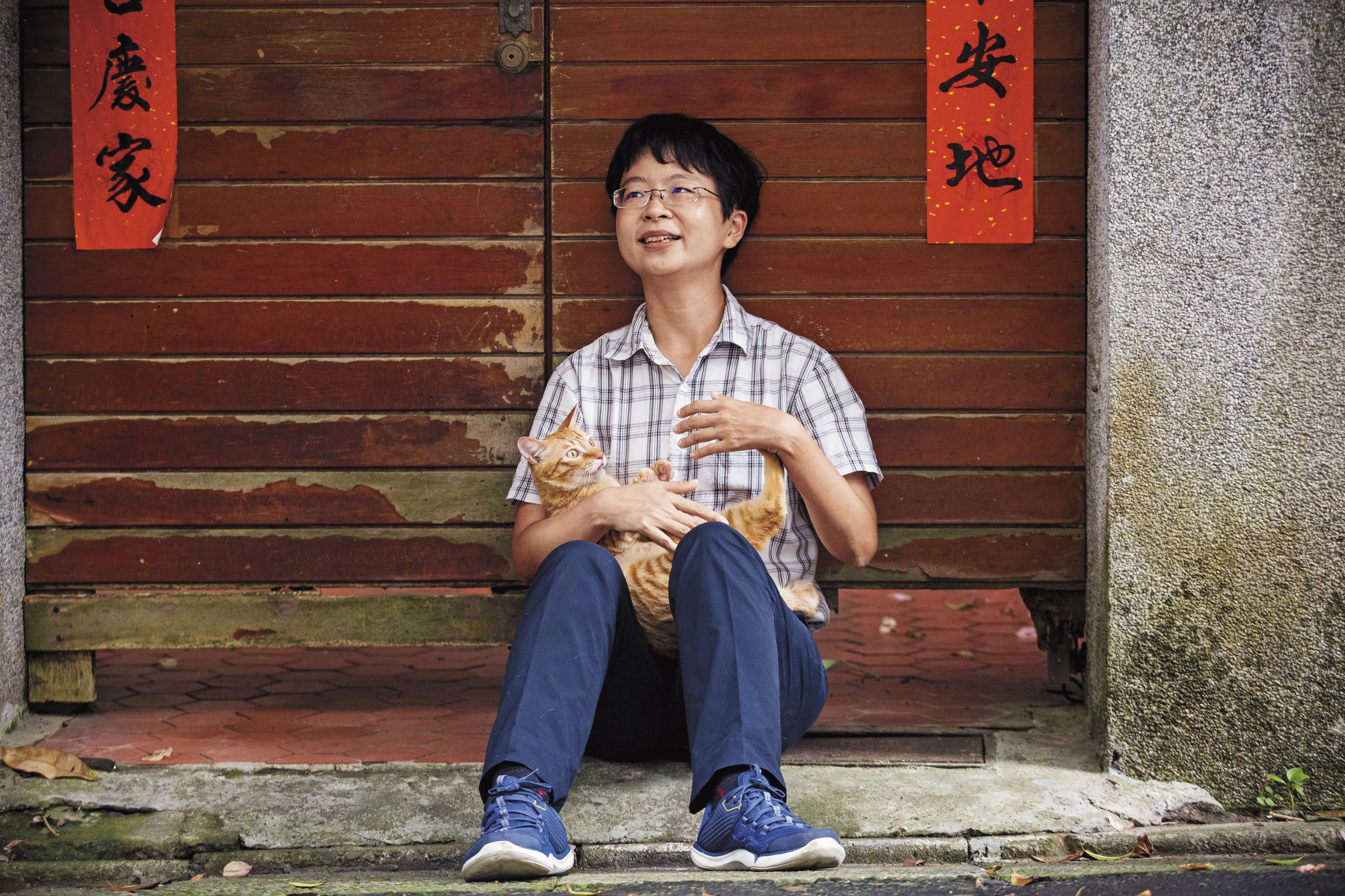 謝海盟在辛亥路老家門口抱起橘貓,霎時露出溫柔笑容,眼神充滿父愛。
