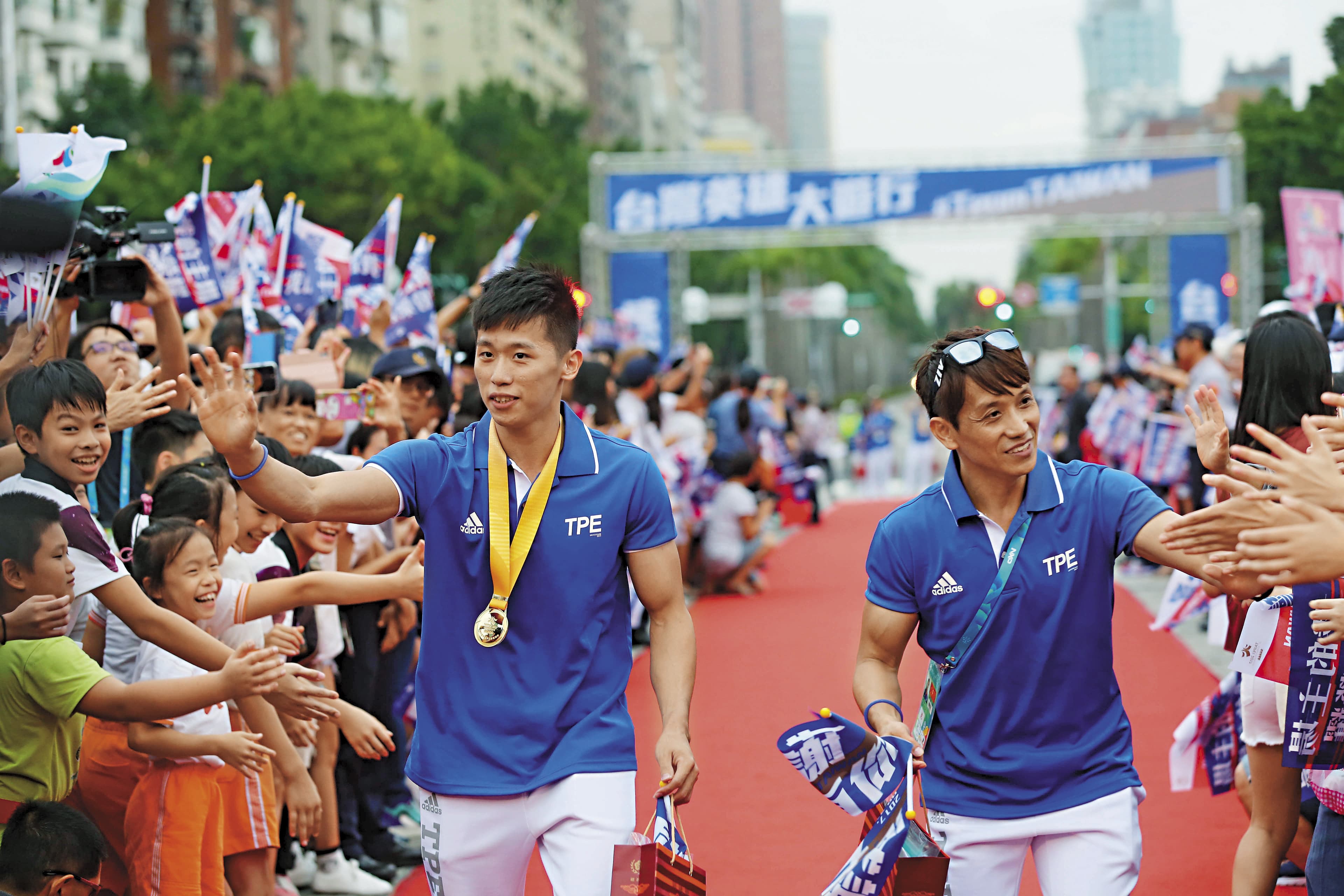 在「世大運台灣英雄大遊行」上,李智凱(左)和林育信(右)一同接受民眾喝彩。