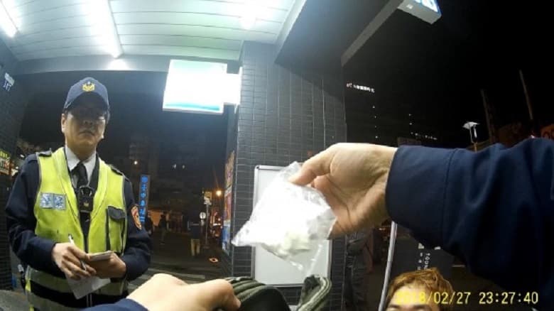 警方在他腳邊的塑膠袋搜出一小塊海洛因與FM2藥丸。(警方提供)