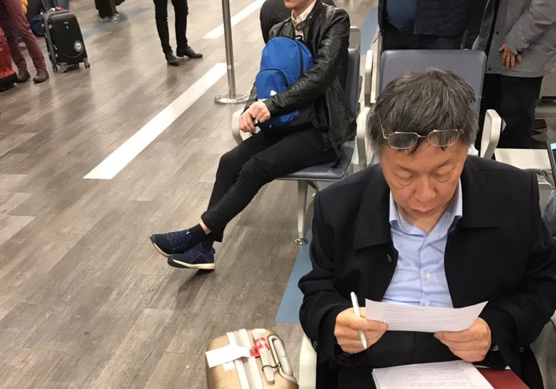 柯文哲這次出訪，被拍到在等機一直埋頭讀資料。（讀者提供）