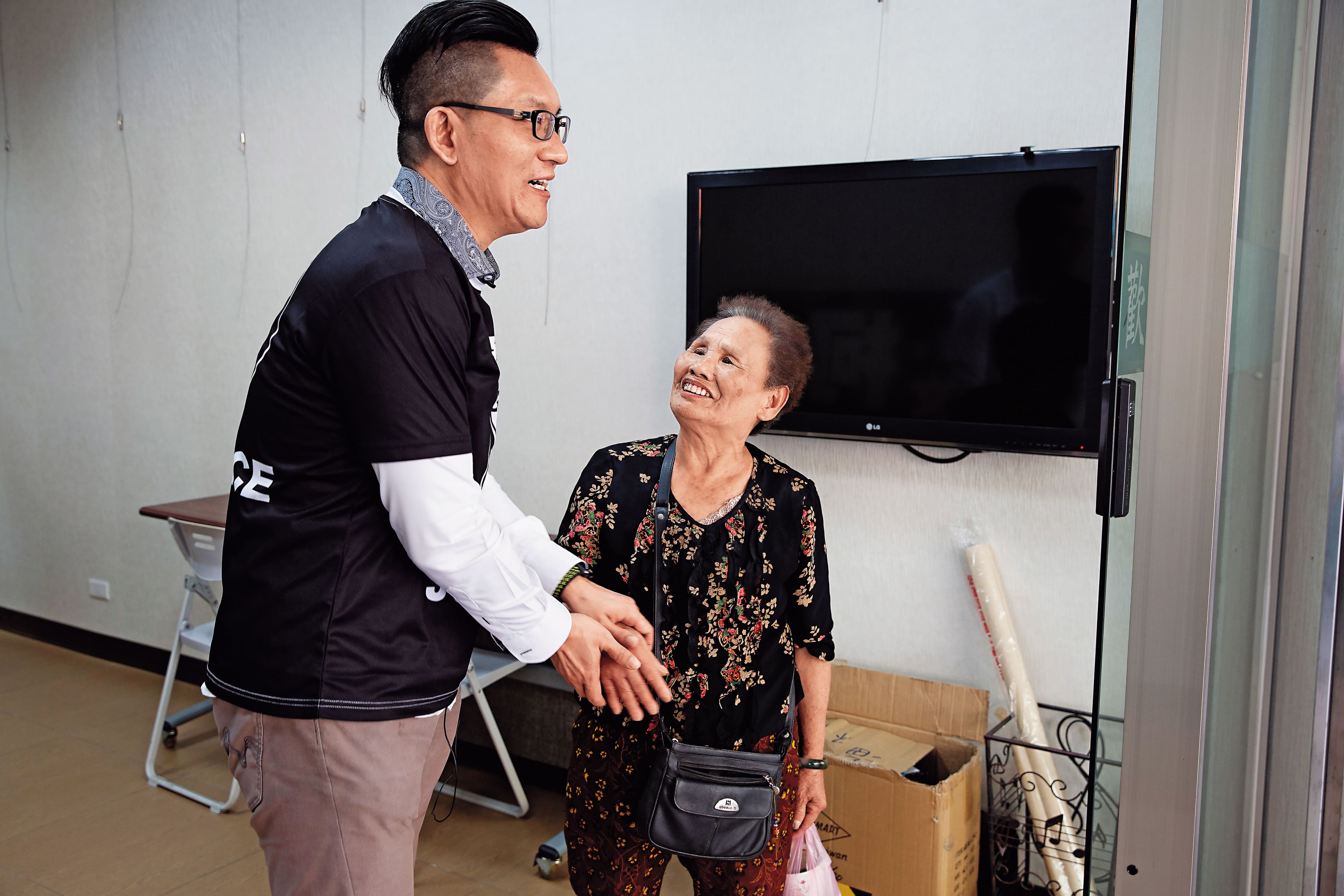 仲彥(左)轉型當網紅,服務處招牌換裝,一名70歲老婦人搞不清楚狀況,亂入表達支持,還希望他重返政壇、選立委。
