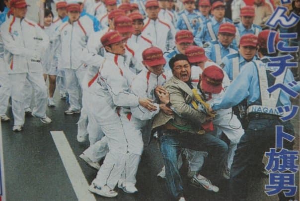 札西慈仁2008年在東京抗議,被警方逮捕時的新聞畫面,日本民間最後幫他籌得50萬日幣的保釋金。(札西慈仁提供)
