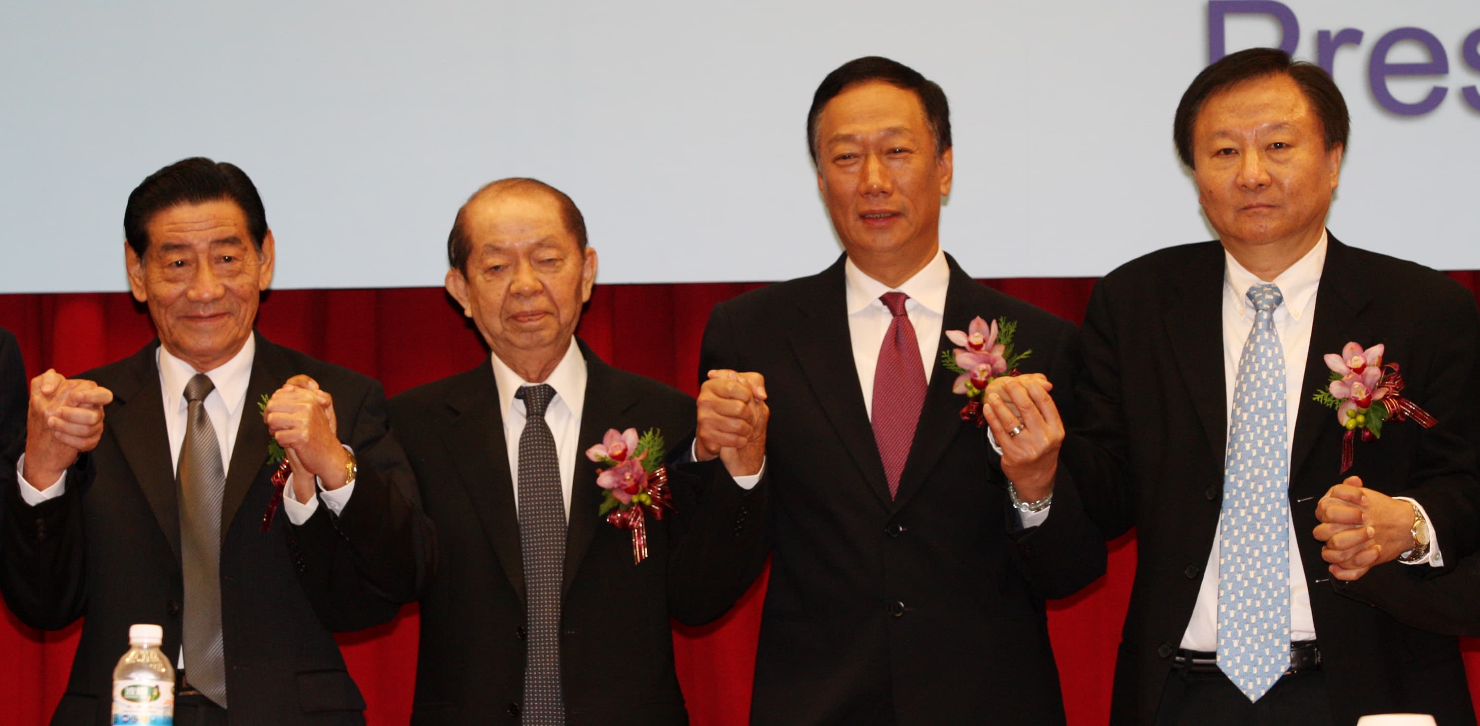 2009年鴻海董事長郭台銘手牽奇美創辦人許文龍，宣布奇美電與群創光電合併。（中央社）