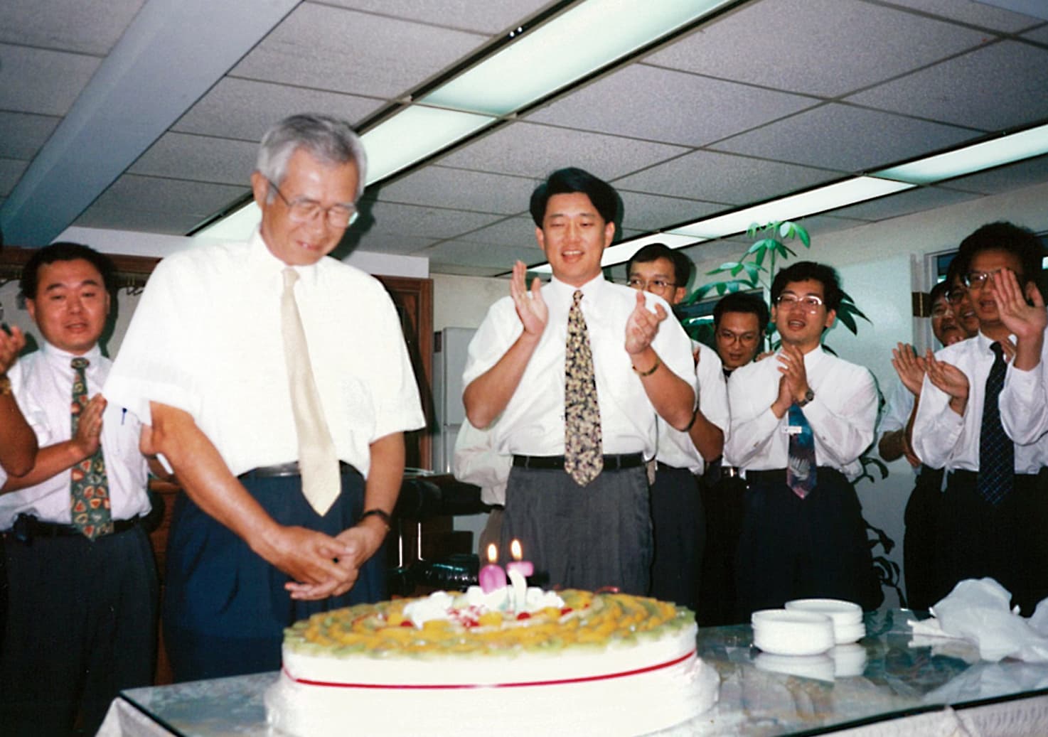 崇越創辦人張永然70歲大壽時，郭智輝（左3）率同仁為他唱生日快樂歌，二人情同父子。（崇越提供）