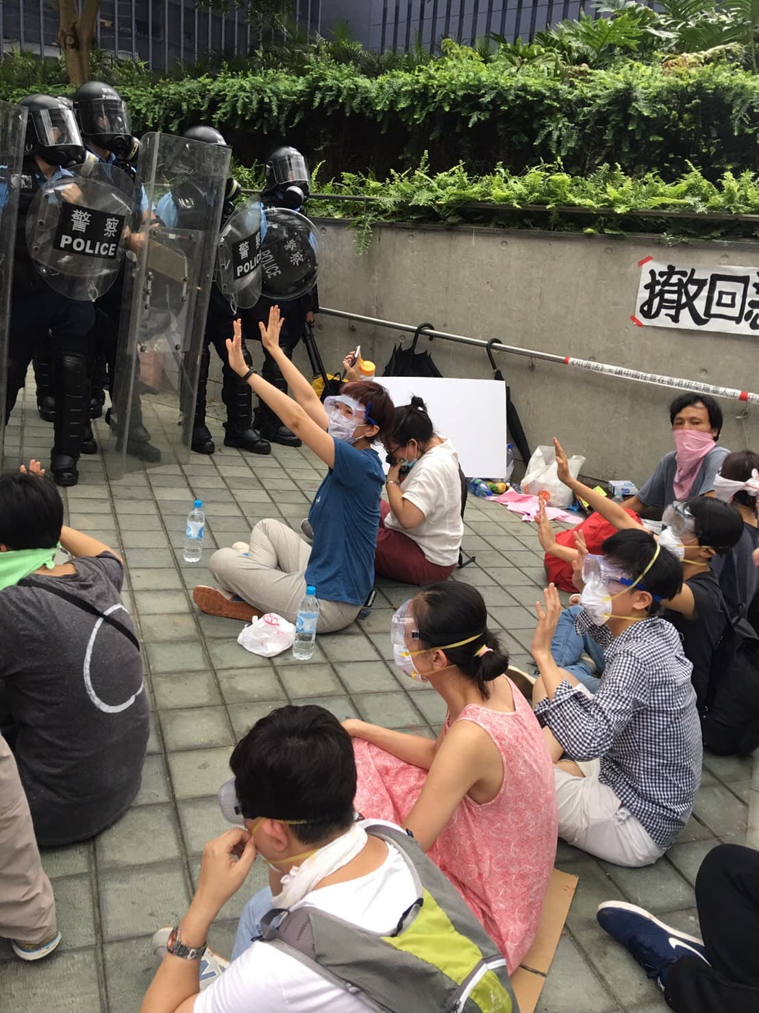 警方開始催淚彈清場後,天橋上的絕食群眾堅持坐在原地,舉手和平示威。