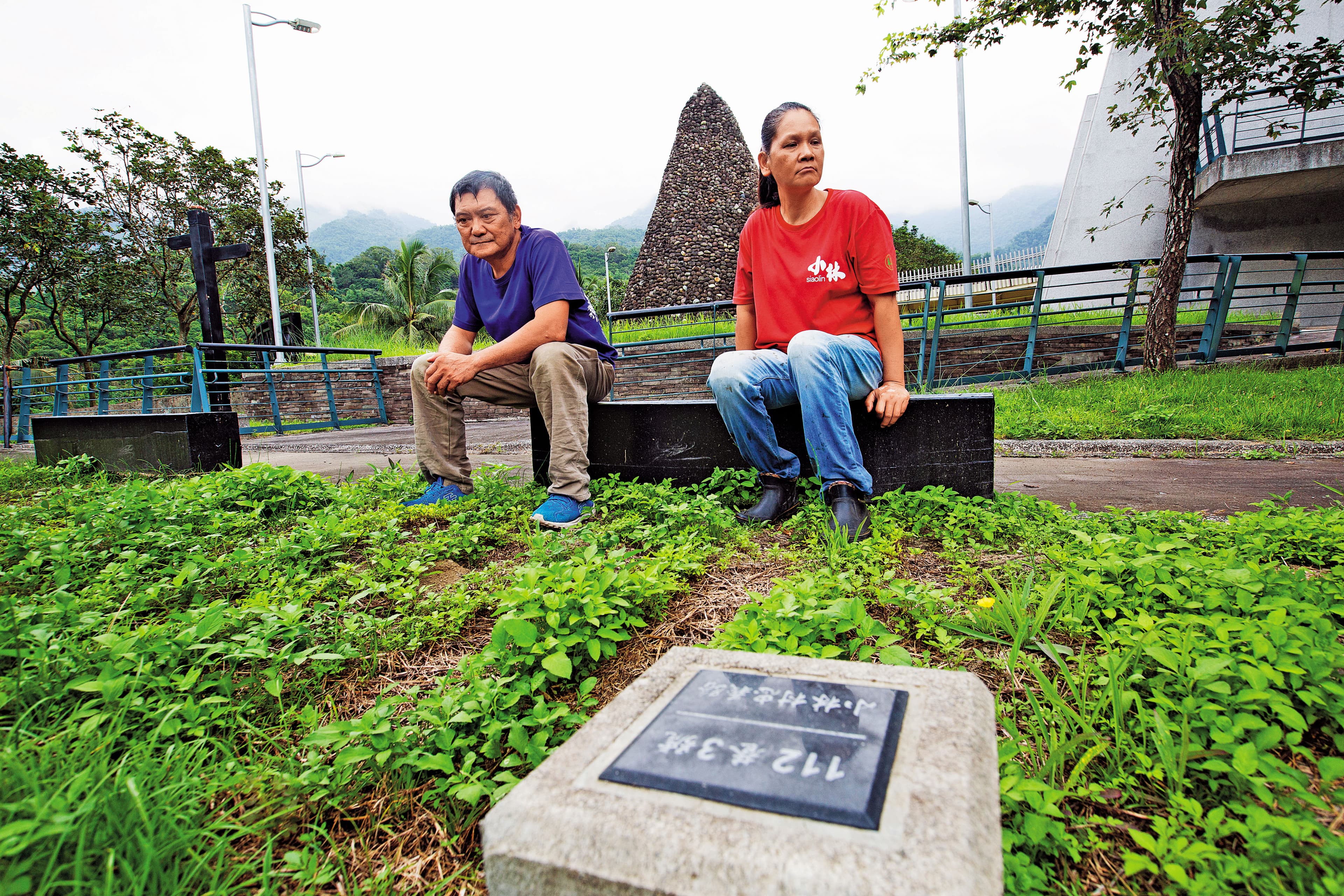 劉秋田(左)坐在紀念公園內,望著老家所在住址忠義路112巷3號,右為太太葉秀霞,也幸運逃出。