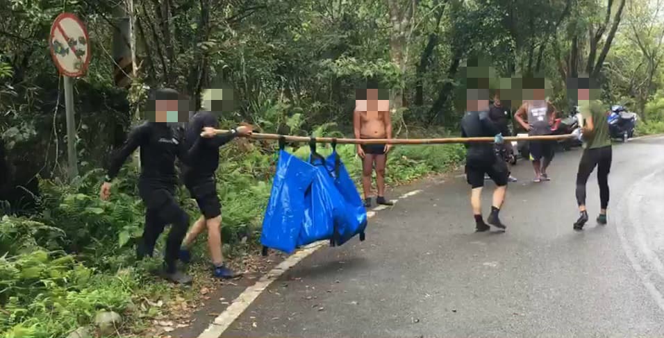 搜救人員費盡力氣才將男童從溪水岩縫中拉出,並送上岸等待檢警相驗。(翻攝畫面)