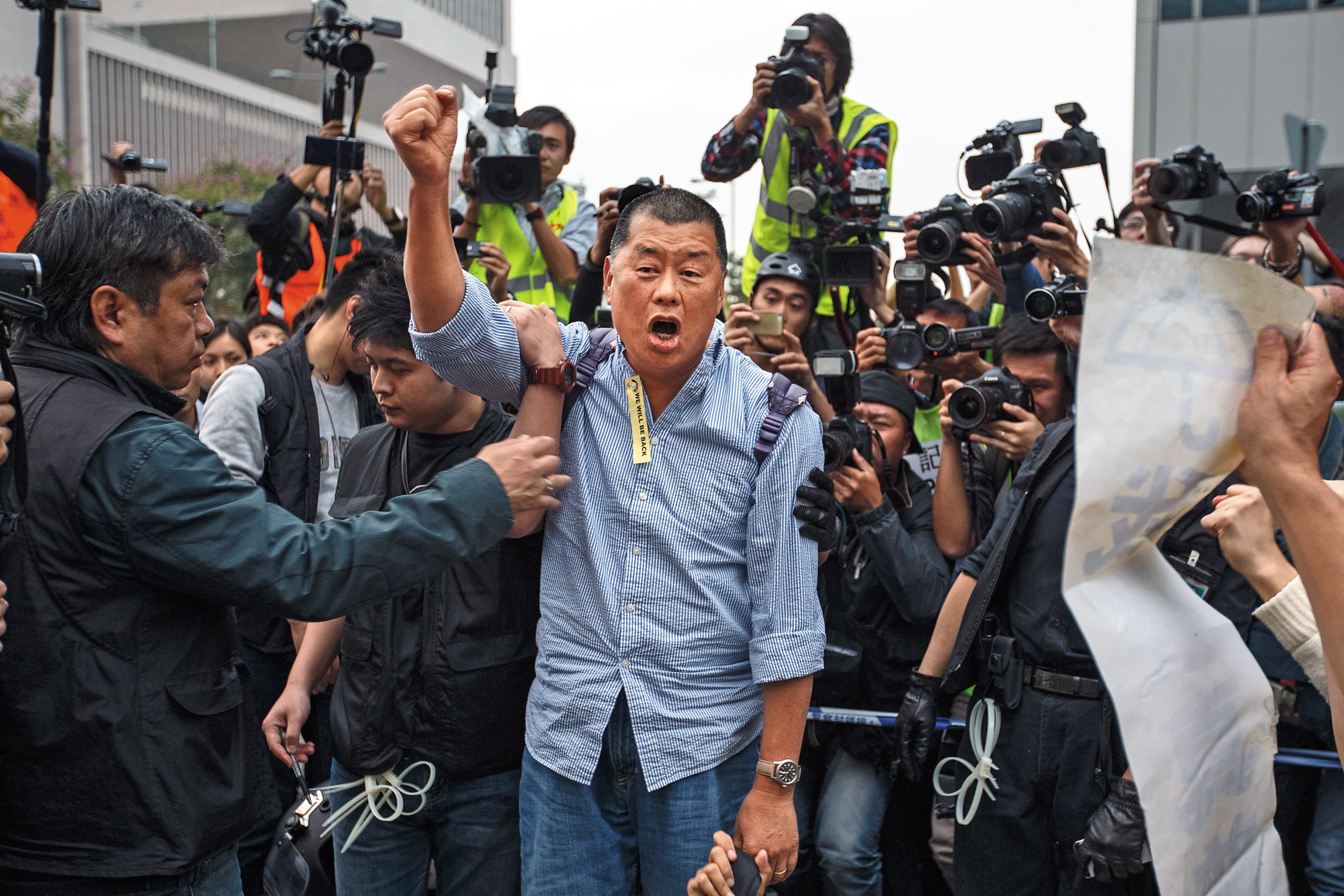 2014年12月11日,占中行動遭到警方強行清場,黎智英堅持在港島金鐘占領區內留守,當他遭警員押走時,仍高喊抗爭口號。(達志影像)
