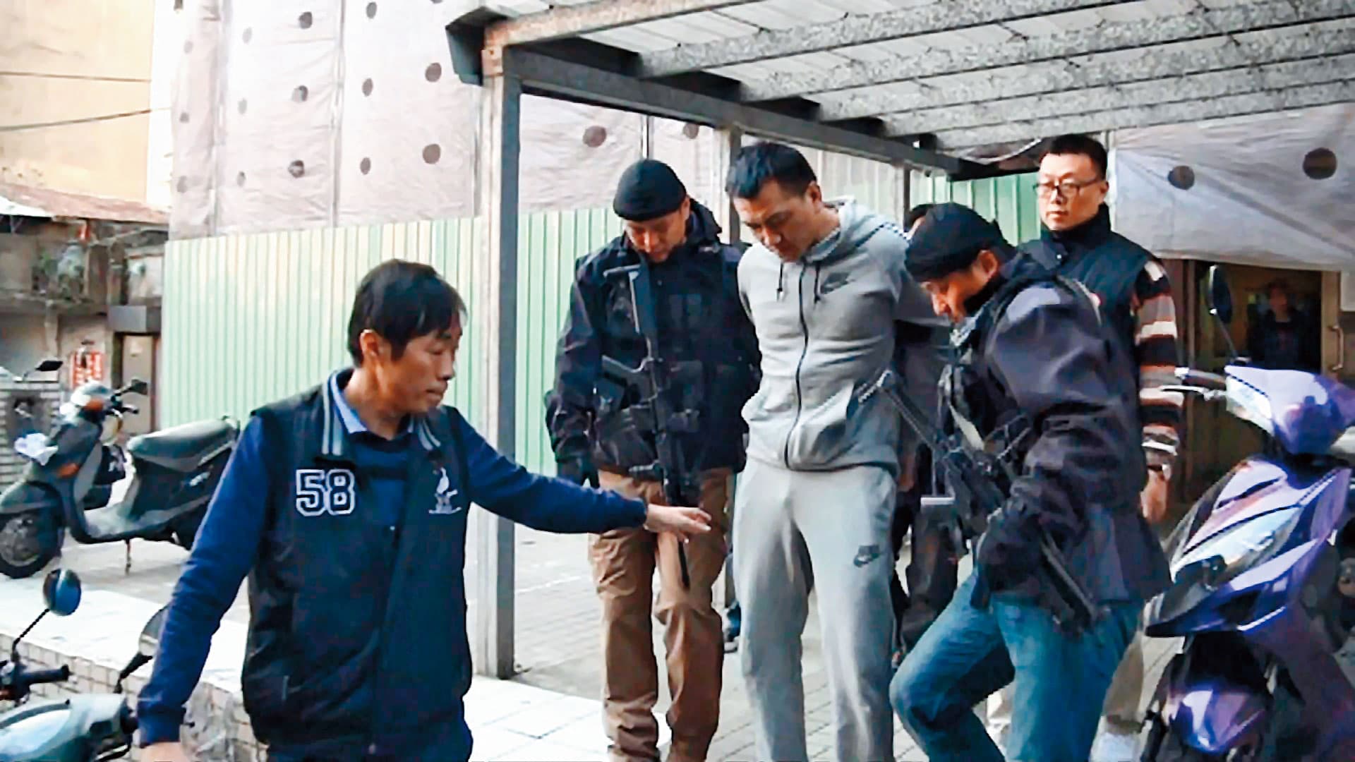 警方將陳福祥(灰衣者)上銬帶回,不費一槍一彈。(東森新聞提供)