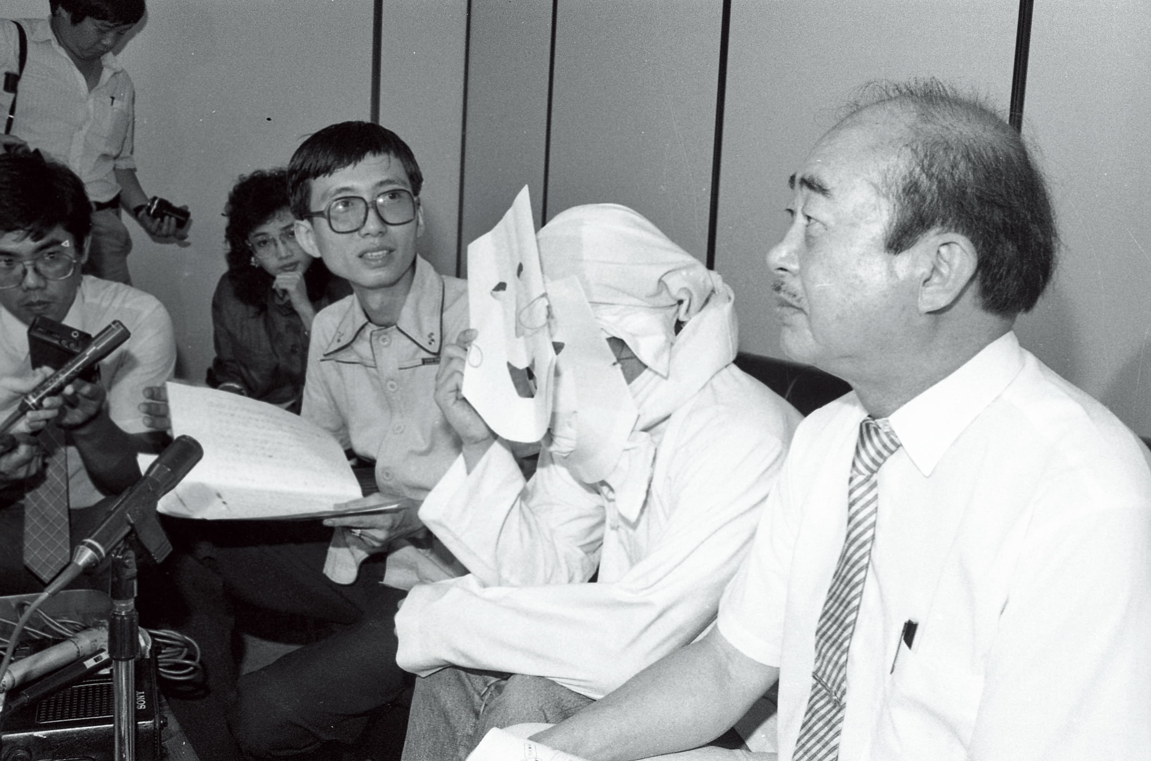 愛滋病汙名很早就開始了,1987年同志運動者祁家威(右3)邀請愛滋感染者(右2)現身呼籲防治愛滋,感染者在鏡頭前也需「全副武裝」。(聯合知識庫)