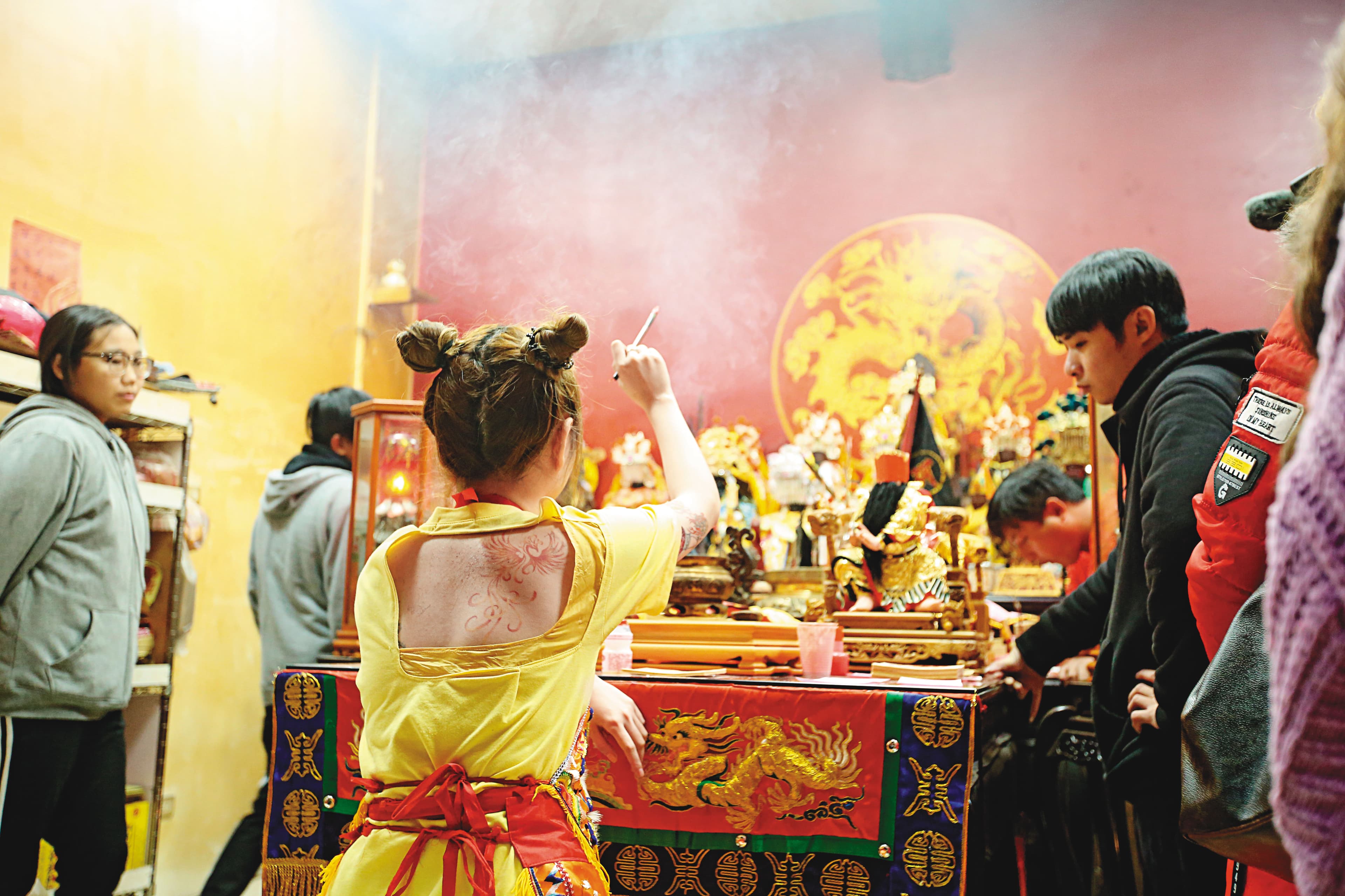 正妹乩童手拿毛筆、蘸上硃砂墨,在空中揮舞,準備替信眾開符令。