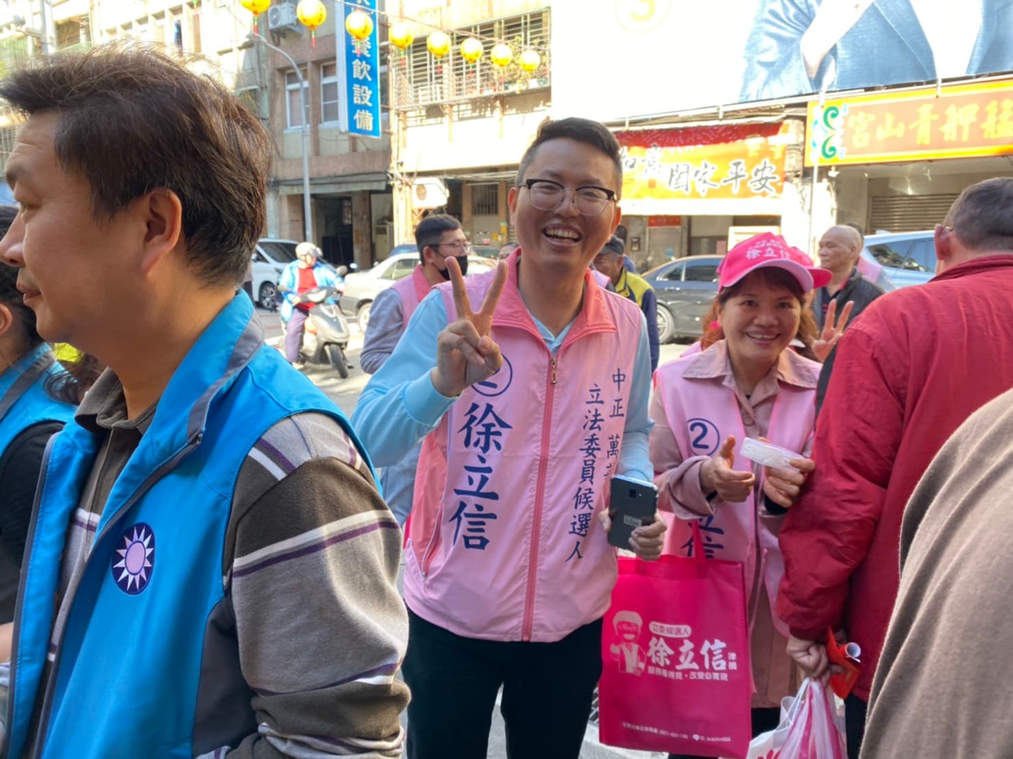 民眾黨的徐立信被藍營眾多的支持者卡在角落,只能無奈比出手勢苦笑。(讀者提供)