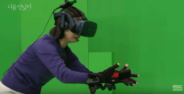 紀錄片中,母親戴著VR眼鏡和觸控手套站在綠幕前和女兒見面。(翻攝Youtube《I Met You》影片)