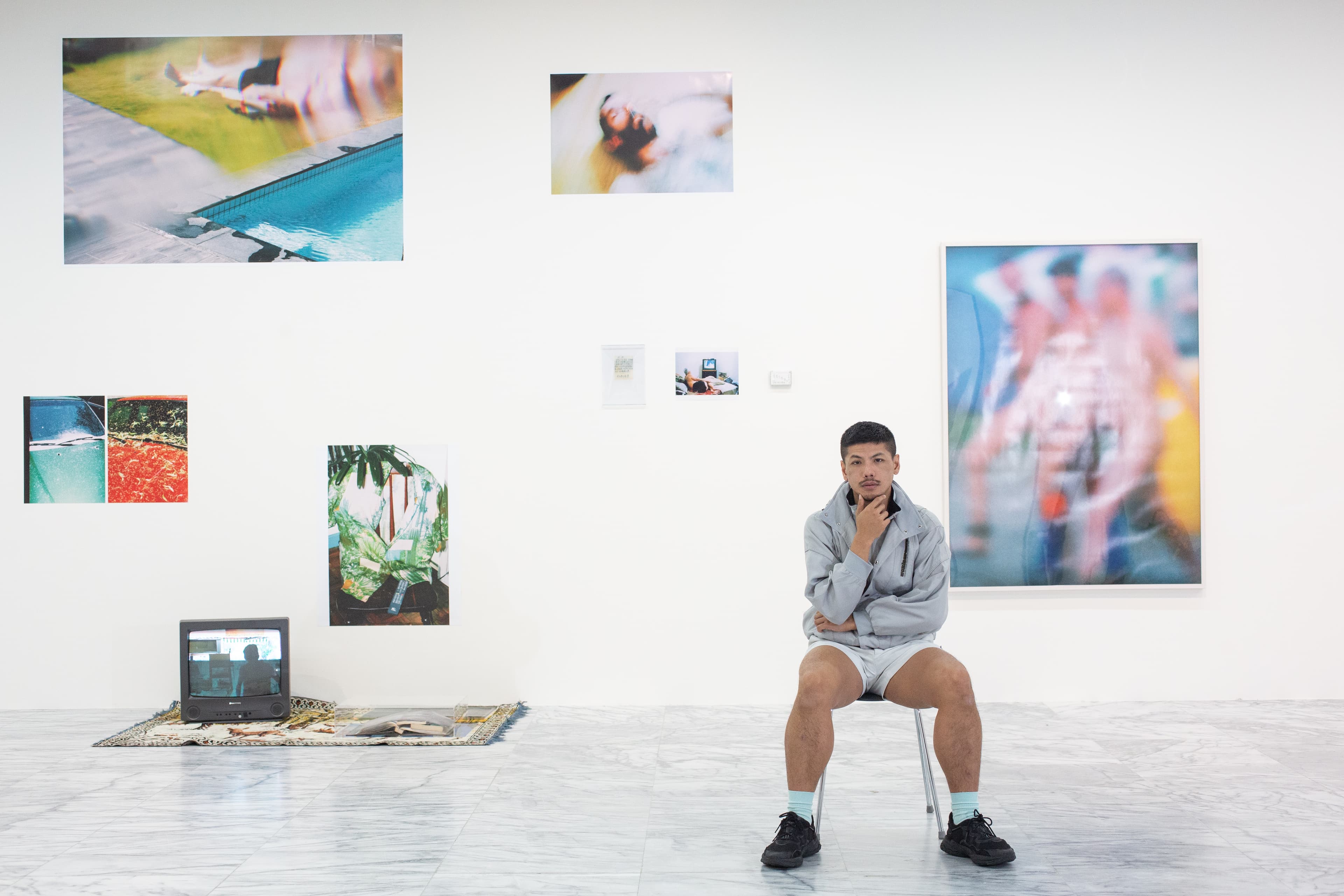 楊登棋在美術館展出台北美術獎首獎作品,背後那面牆上照片是他所拍,繽紛多彩:「照片是我的日記,我很想跟爸爸分享我的生活,但他始終難以啟齒,其實沒辦法真的對話。」
