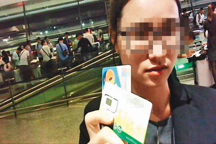 預付卡代理商(圖)拿著2張預付卡,以越南話指示移工在申辦單畫圈處簽名。(爆料影片截圖)