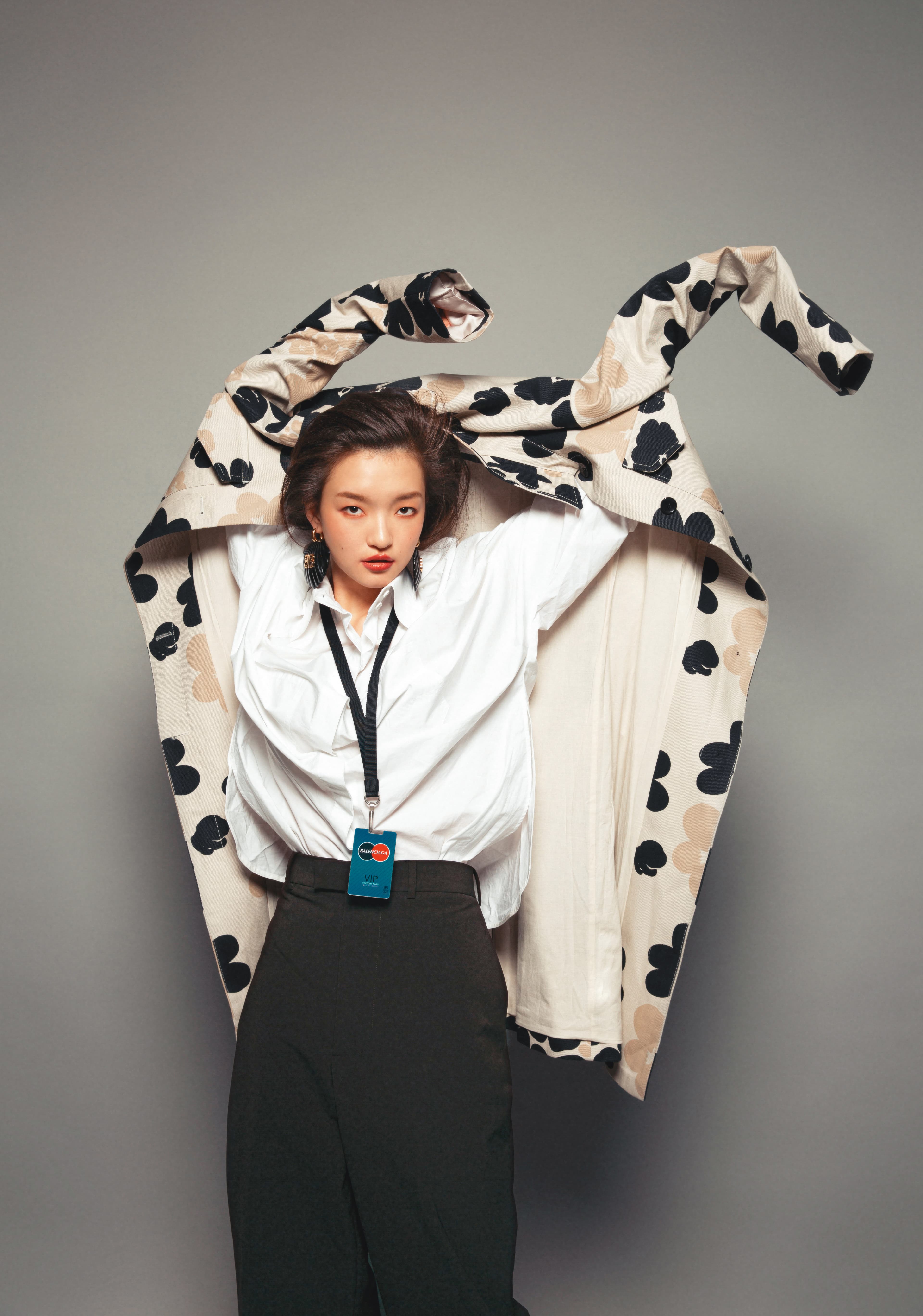 Kevättalkoot印花風衣外套 NT$18,680 by marimekko；白色襯衫 價格未定 by FENDI；巧克力棕混紡寬褲 NT$40,000 by Bottega Veneta；BB黑色美人魚耳環 NT$30,100 by BALENCIAGA；訪客造型項鍊 價格未定 by BALENCIAGA。