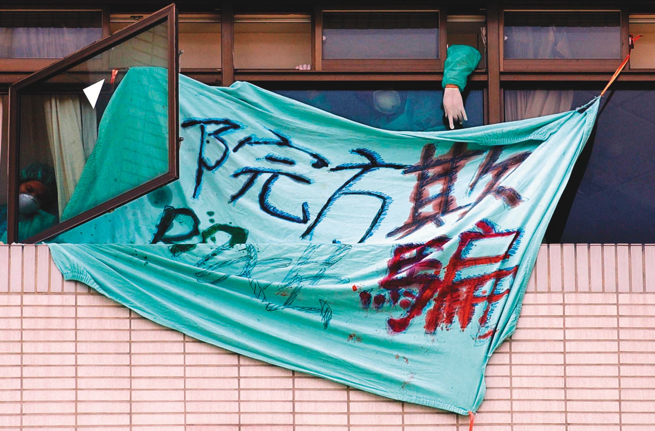 2003年,因SARS疫情台北市和平醫院封院,被隔離的病患家屬在窗外拉布條抗議院方隱瞞疫情。(中央社)