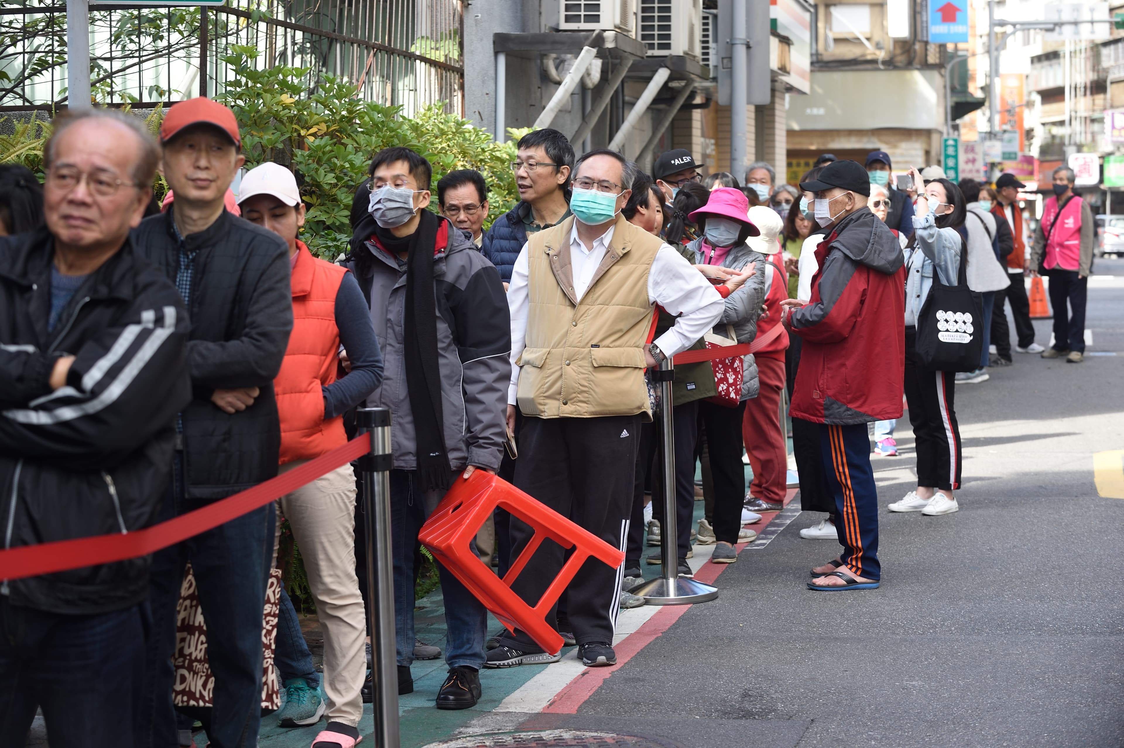許多台灣民眾攜帶健保卡到藥局排隊購買口罩。(本刊資料照)