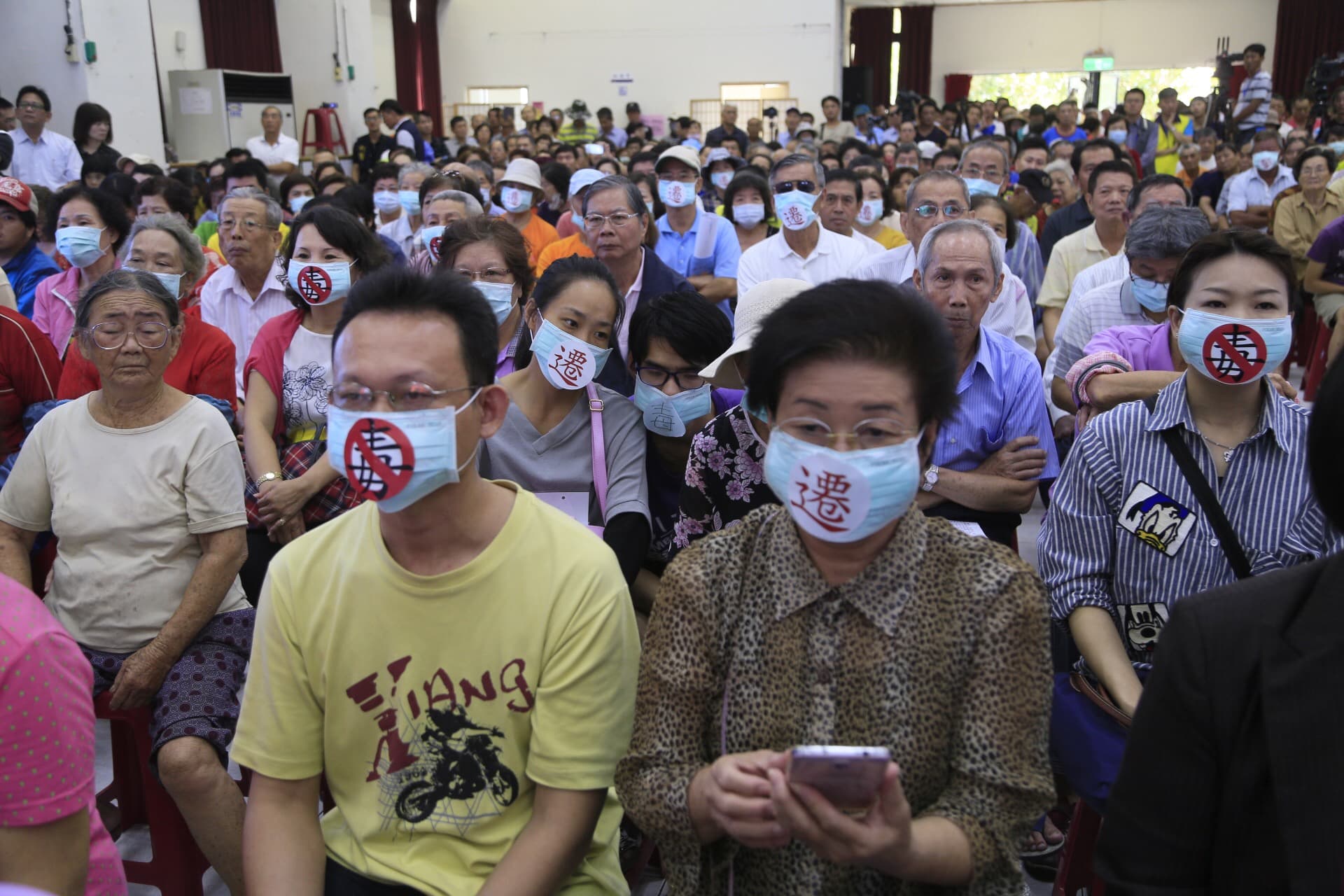 2016年,時任行政院長林全與高雄市長陳菊前往大林蒲鞠躬道歉,並開座談會傾聽民意,當地居民戴上口罩抗議環境汙染。(中央社)