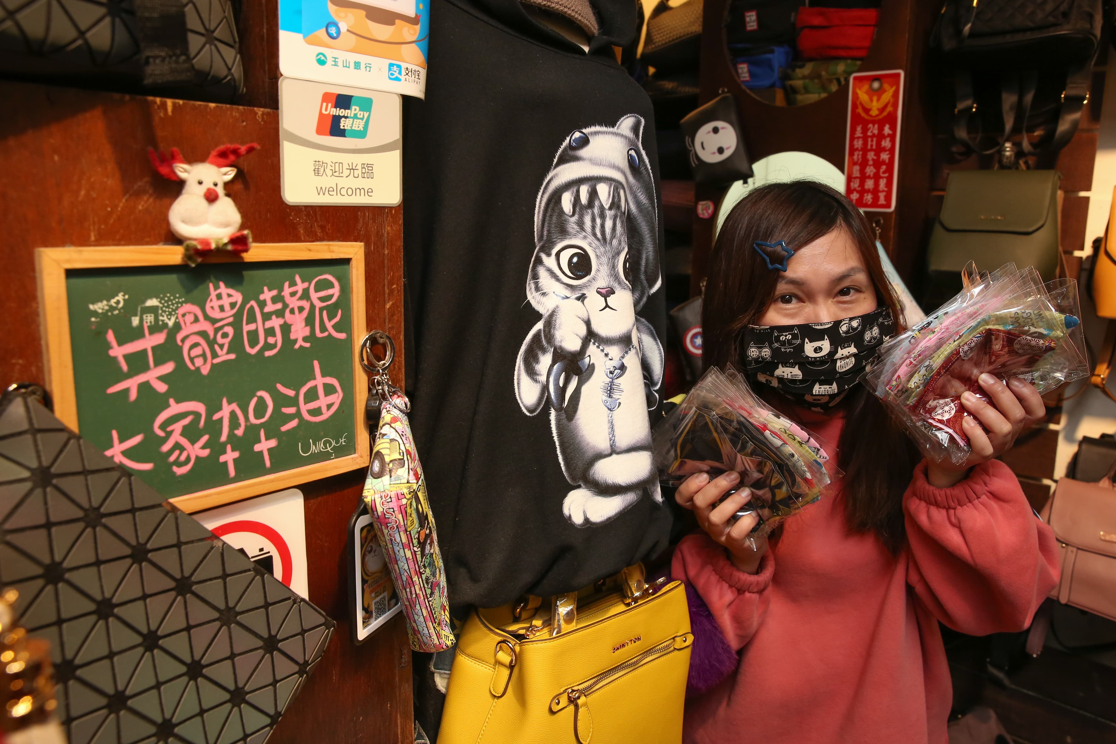 「夜上海」服飾店的老闆娘張玲華受訪,身旁放著一塊寫了「共體時艱,大家加油」的小黑板。
