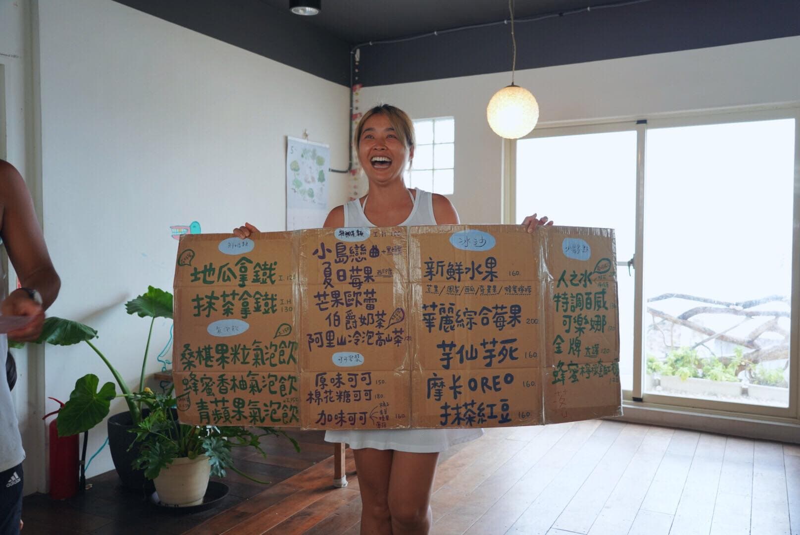 小嫻人在蘭嶼舉著飲料菜單紙牌,笑得非常燦爛。(翻攝自隋棠 Sonia Sui臉書)