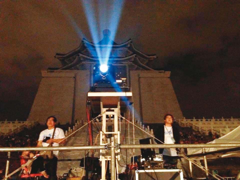 江泰暾(左)在《看見台灣》萬人首映活動中,全神貫注工作。(江泰暾提供)