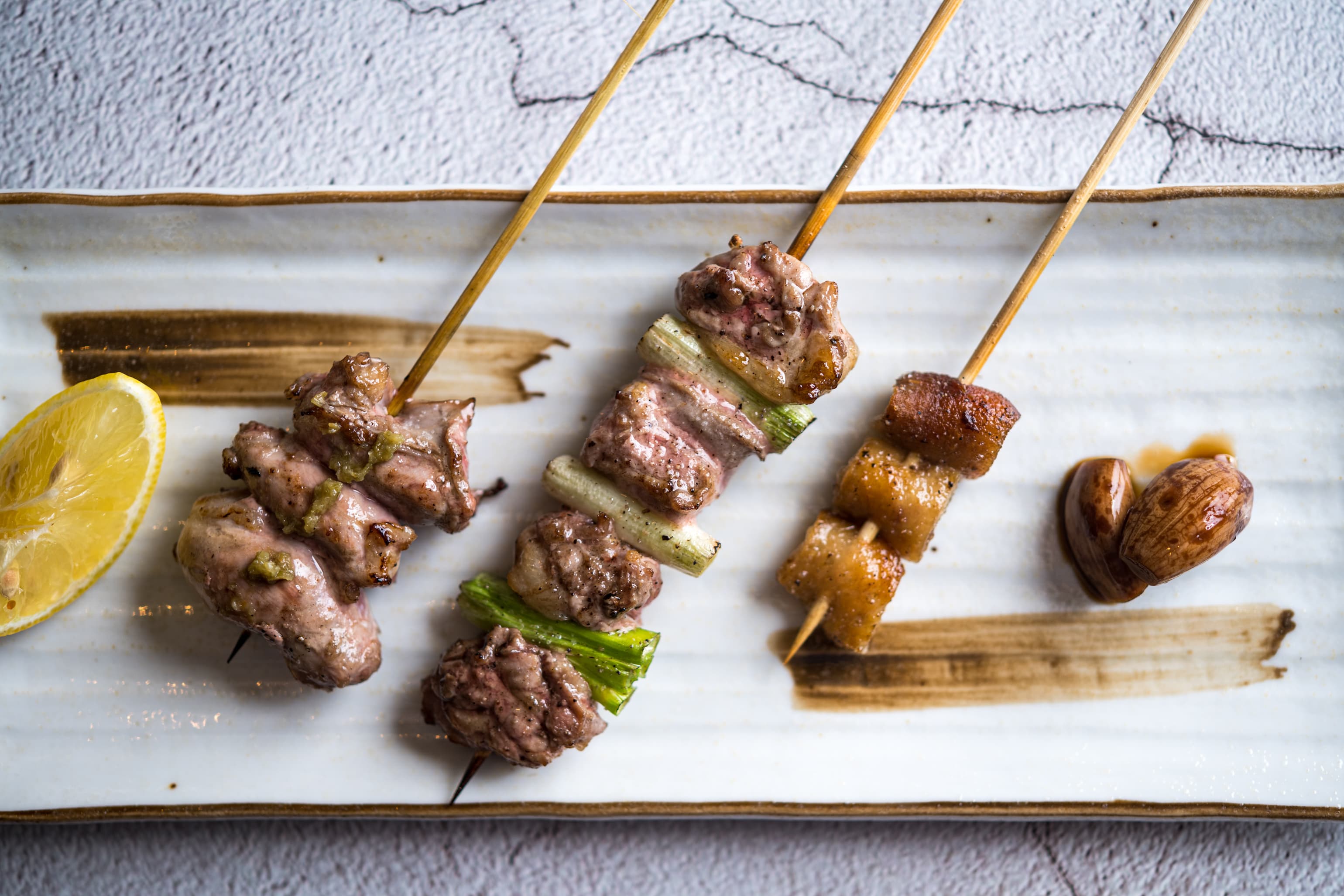 John用鴨皮、腿肉佐蔥、阿基里斯腱佐柚子胡椒的「三種鴨腿串燒」呼應混釀芋燒酎的三種面貌。(300元/份)