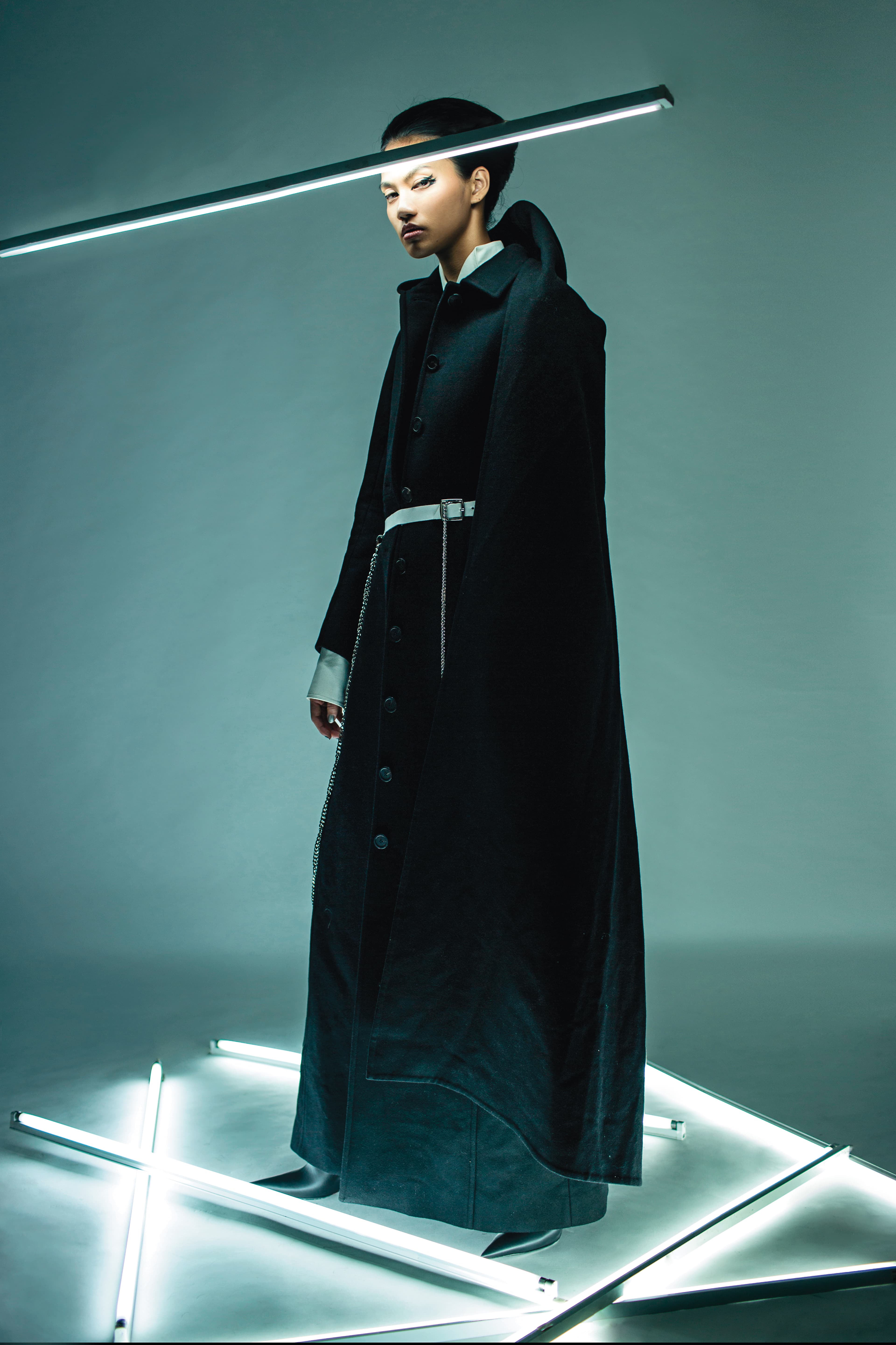 黑色連帽大衣 NT$233,400 by BALENCIAGA／2件式 洋裝NT$88,000 by LOEWE／黑色尖頭靴 價格店洽 by BALENCIAGA／白色鍊條腰帶 NT$4,580 by Phoenix Yang。
