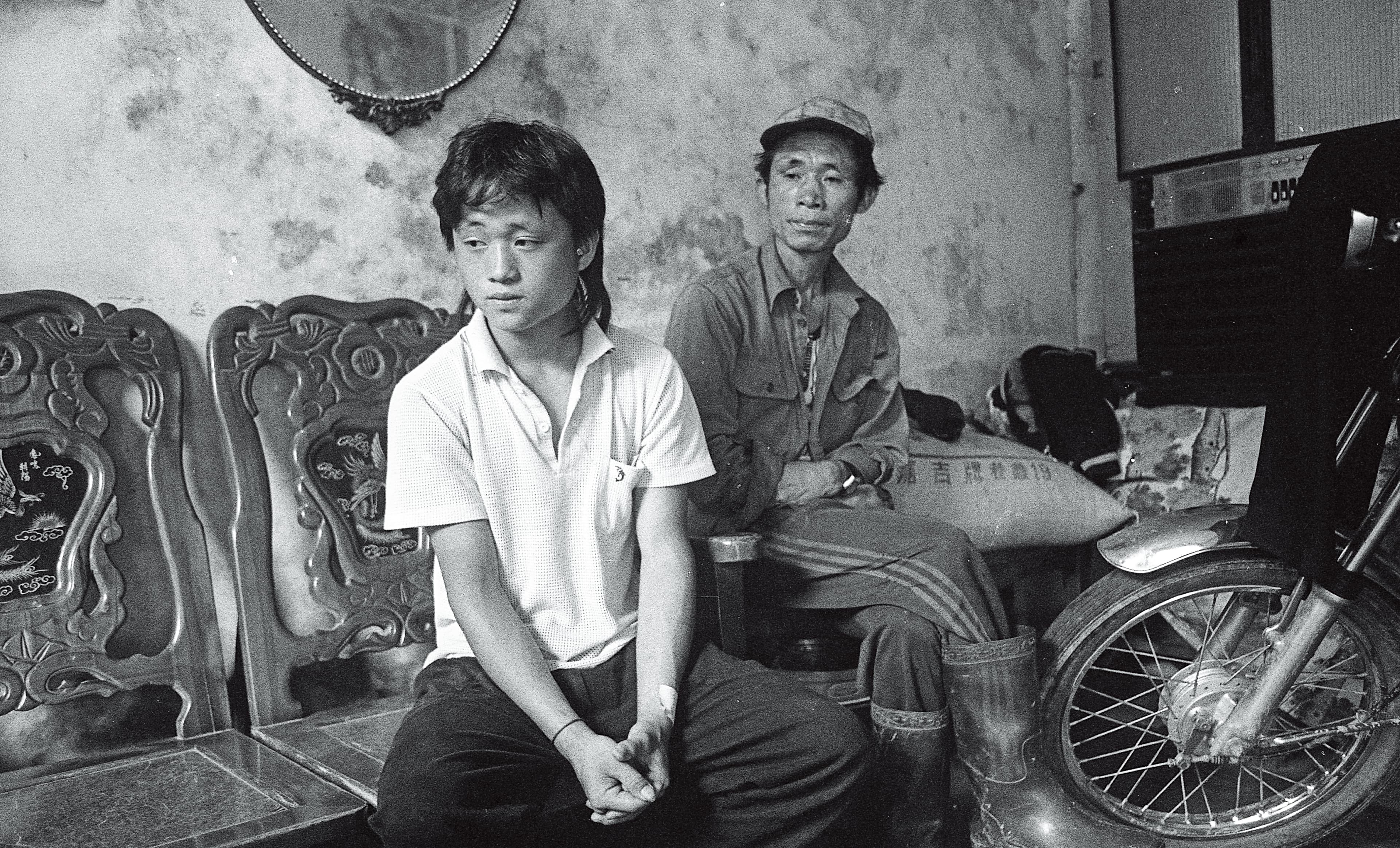 1988年,周子飛的二哥張文星(左)與生父周瑞霖(右)一同在家中接受訪問。周瑞霖因酗酒,於多年前亡故。(蔡明德攝)