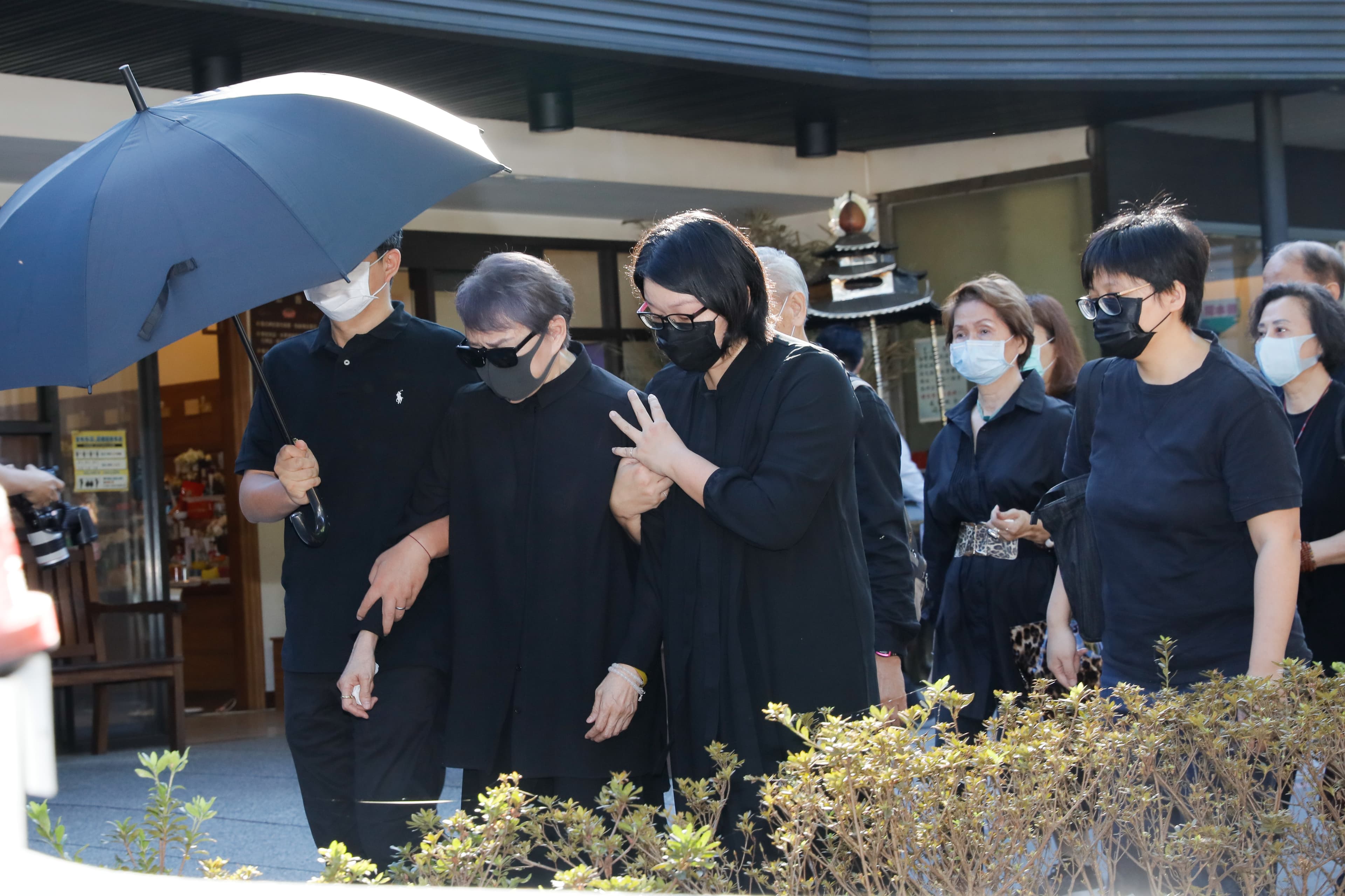 楊惠姍由家人撐著黑傘，攙扶她回休息室。