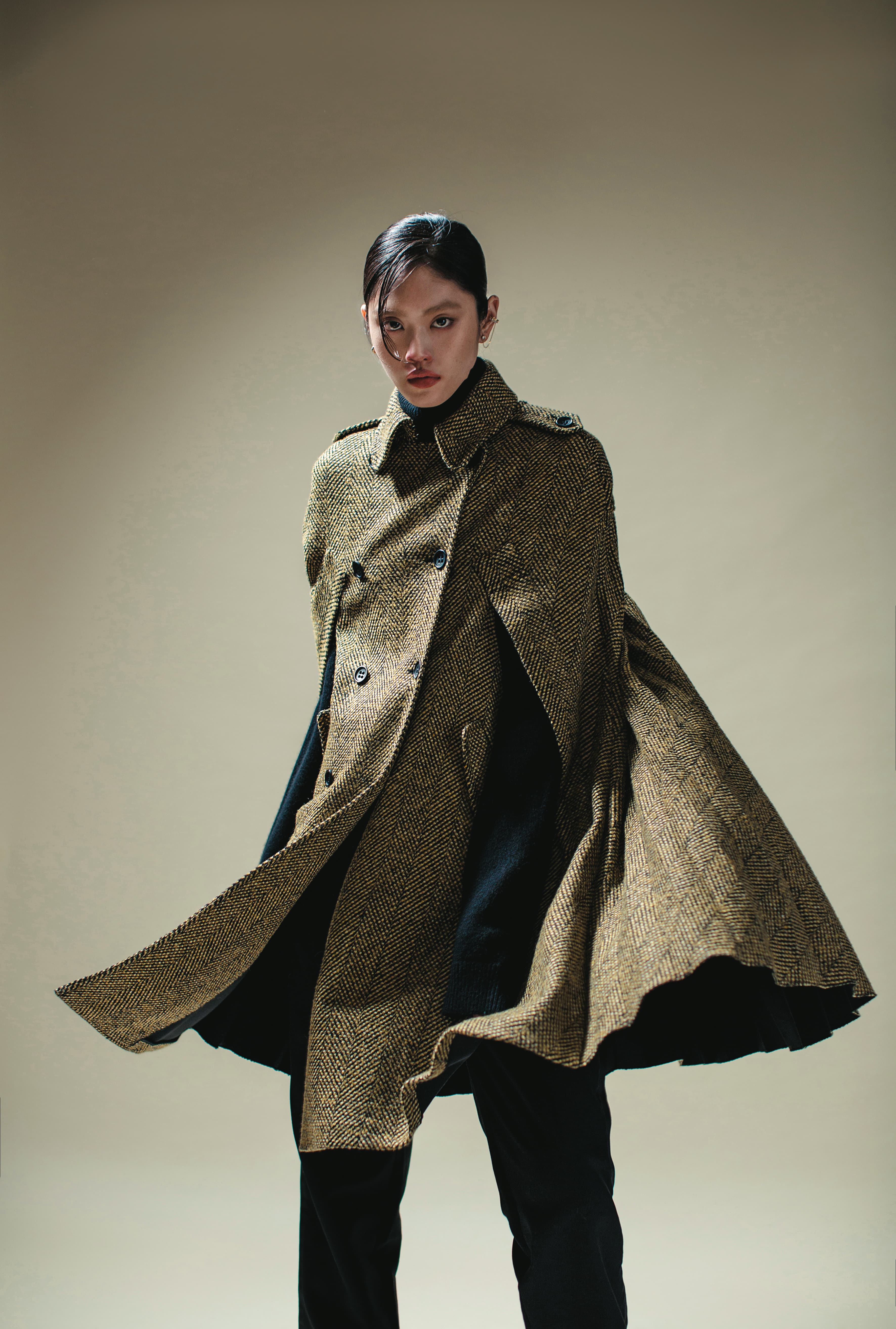 黃色格紋斗篷 價格店洽 by REDValentino／黑色高領毛衣 價格店洽 by MICHAEL MICHAEL KORS／黑色長褲 價格店洽 by LOEWE／TIME穿孔耳環 NT$3,490 by SWAROVSKI