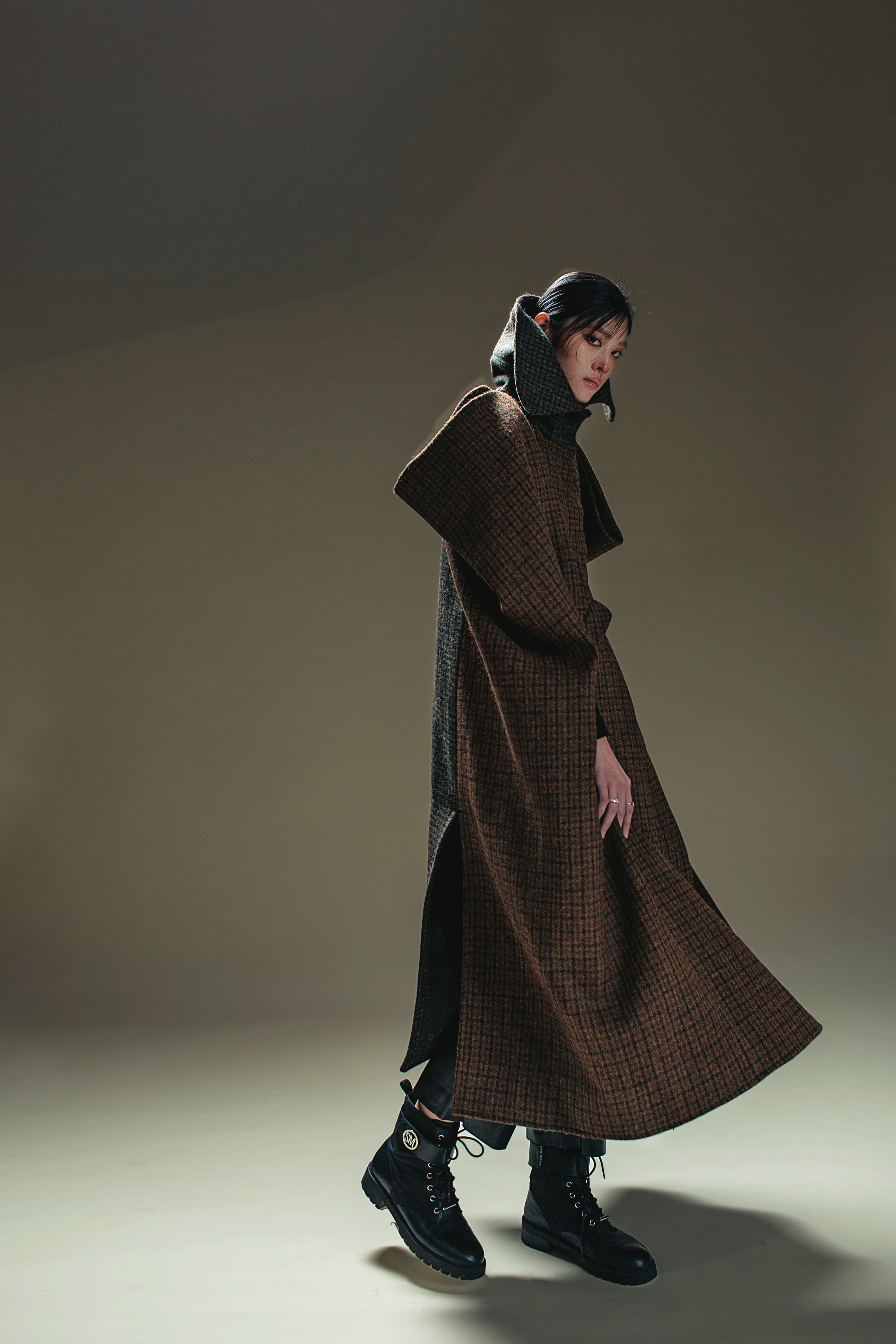 立體剪裁格紋拼接斗篷 價格店洽 by LOEWE／黑色皮長褲 NT$22,950 by SANDRO／黑色靴子 私物／VITTORE戒指 NT$6,490 by SWAROVSKI／MAGIC戒指 NT$5,990 by SWAROVSKI