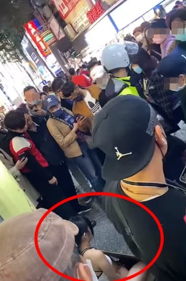 女子在街頭的行徑引發不少人駐足,還有警察到場關切。(翻攝自「爆廢公社2館」臉書)