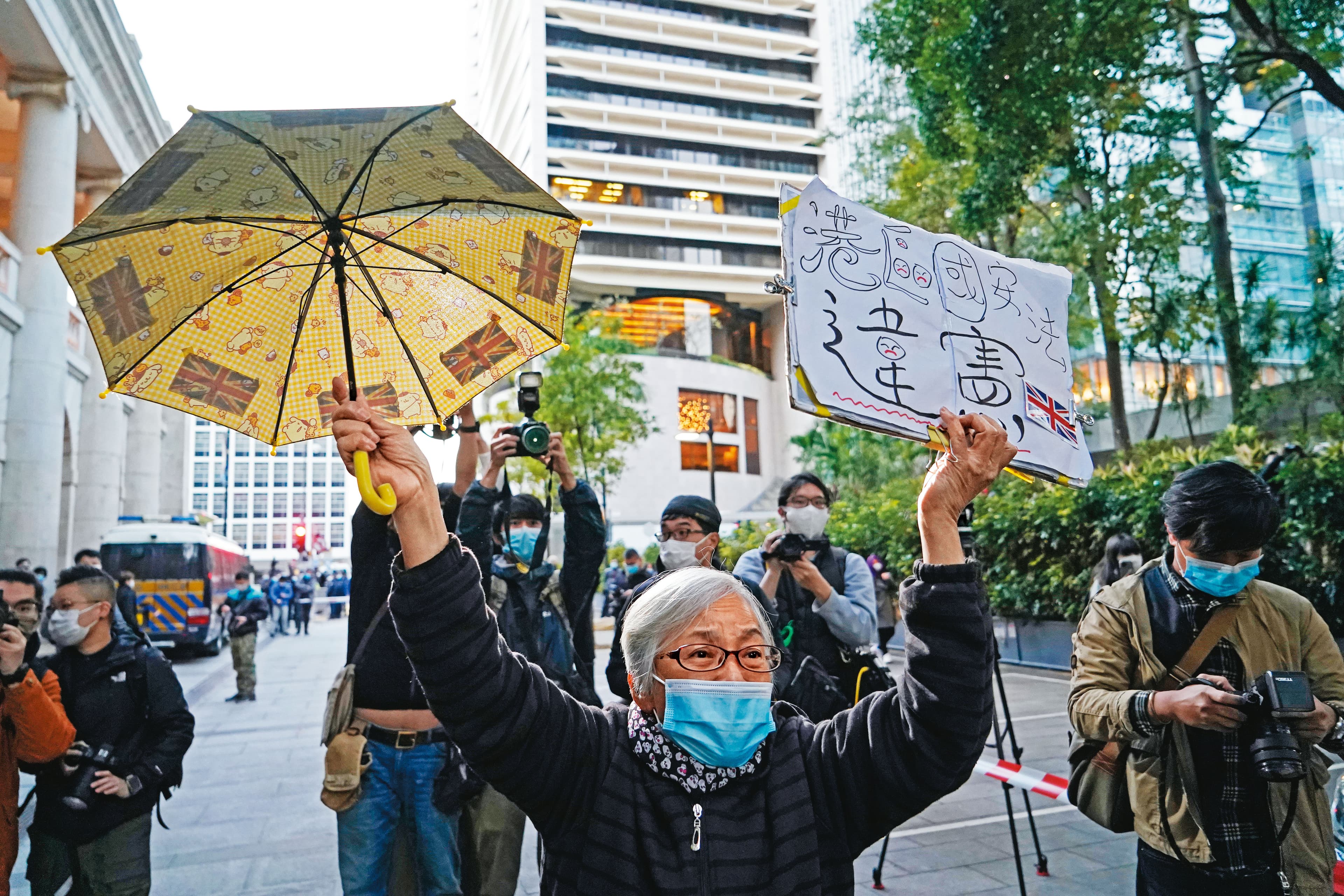 香港知名社運人士「王婆婆」曾聲援黎智英。圖為她高舉黃傘與自製的「港區國安法違憲」標語牌。(達志影像)