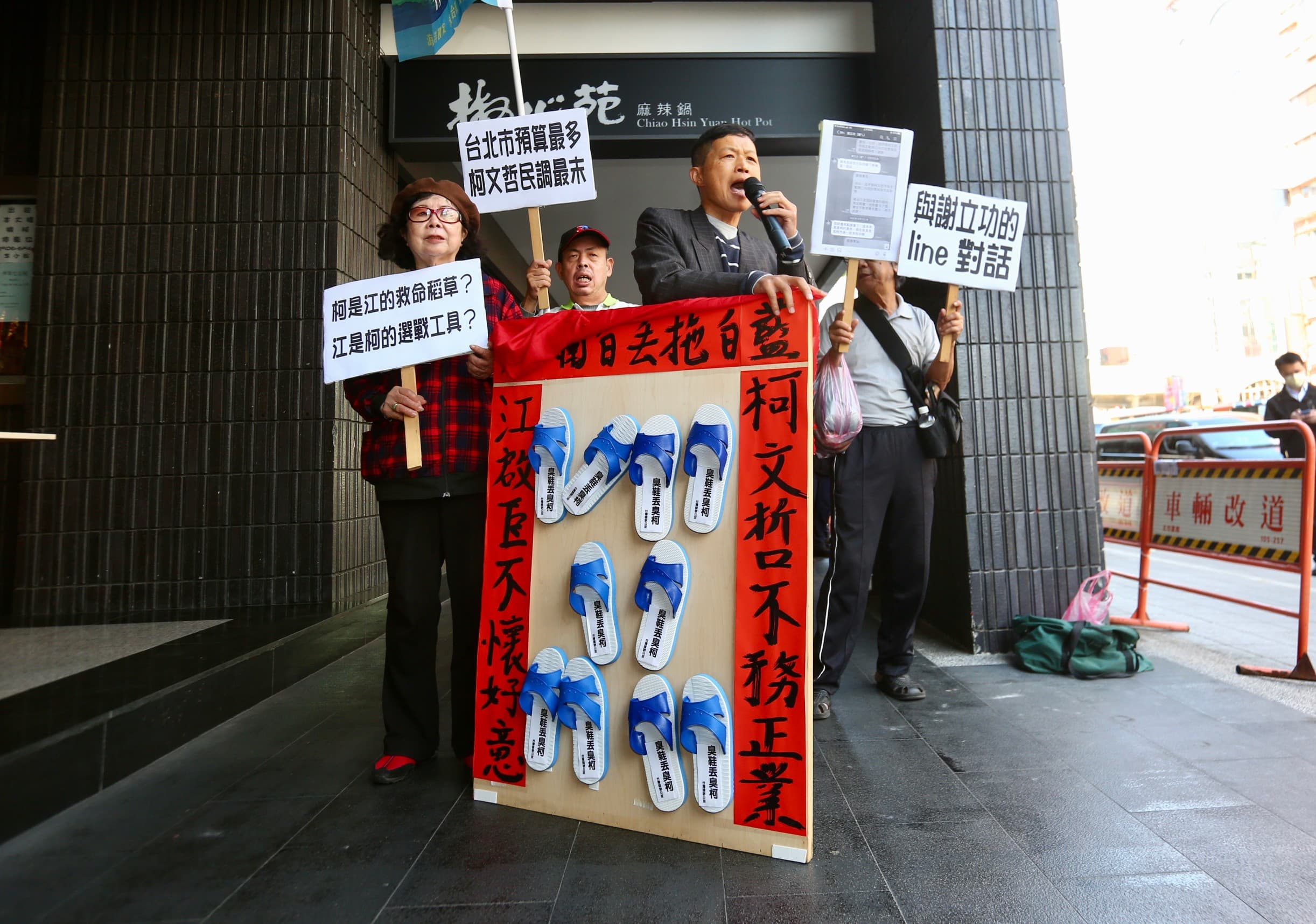 柯文哲、江啟臣24日上午出席願景台灣2030論壇活動,場外台灣國成員眾以藍白拖暗喻藍白各懷鬼胎。
