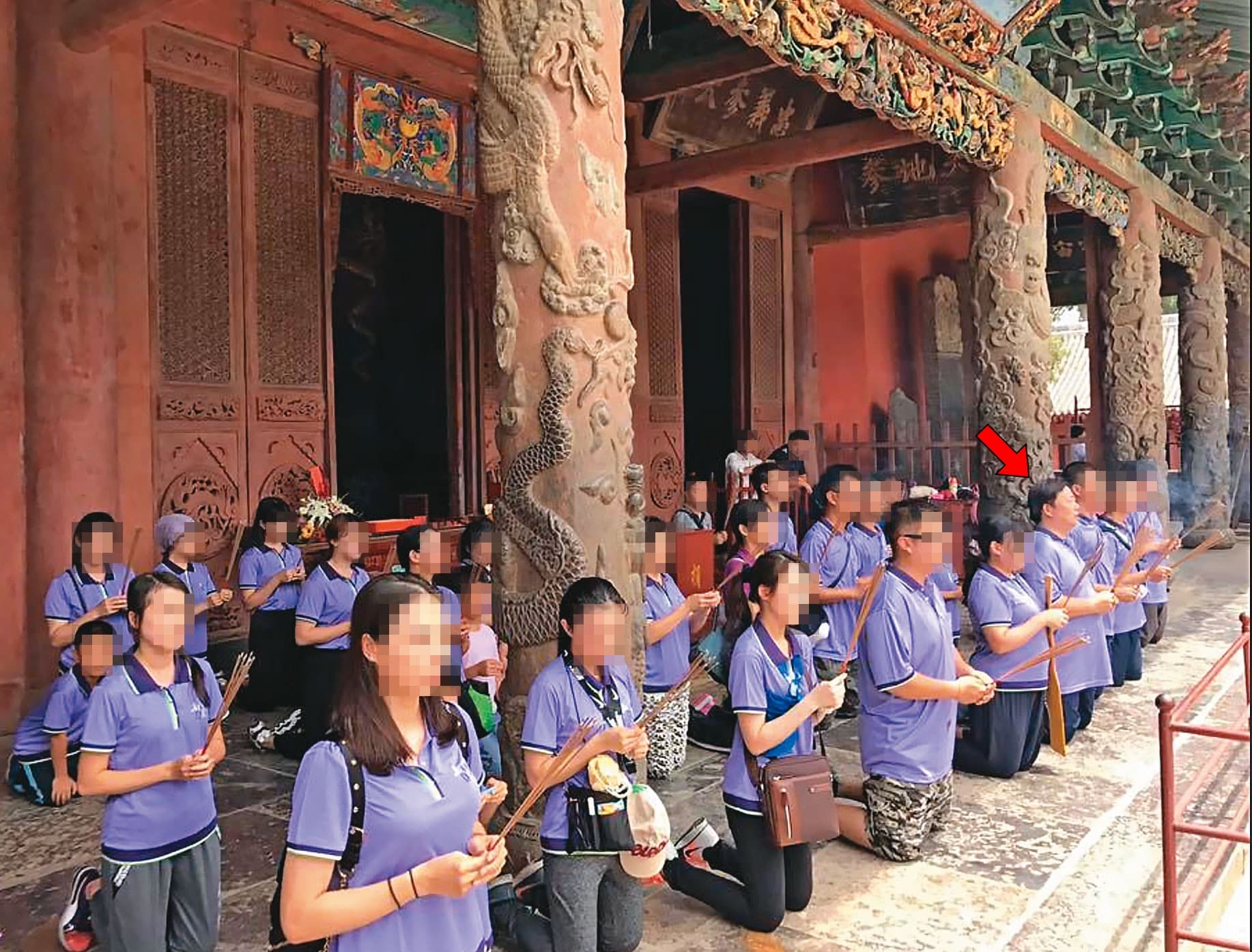 袁子洺(箭頭處)帶領信徒團拜,妻子和同住宮廟2樓的女性密友也一同入鏡。(讀者提供)